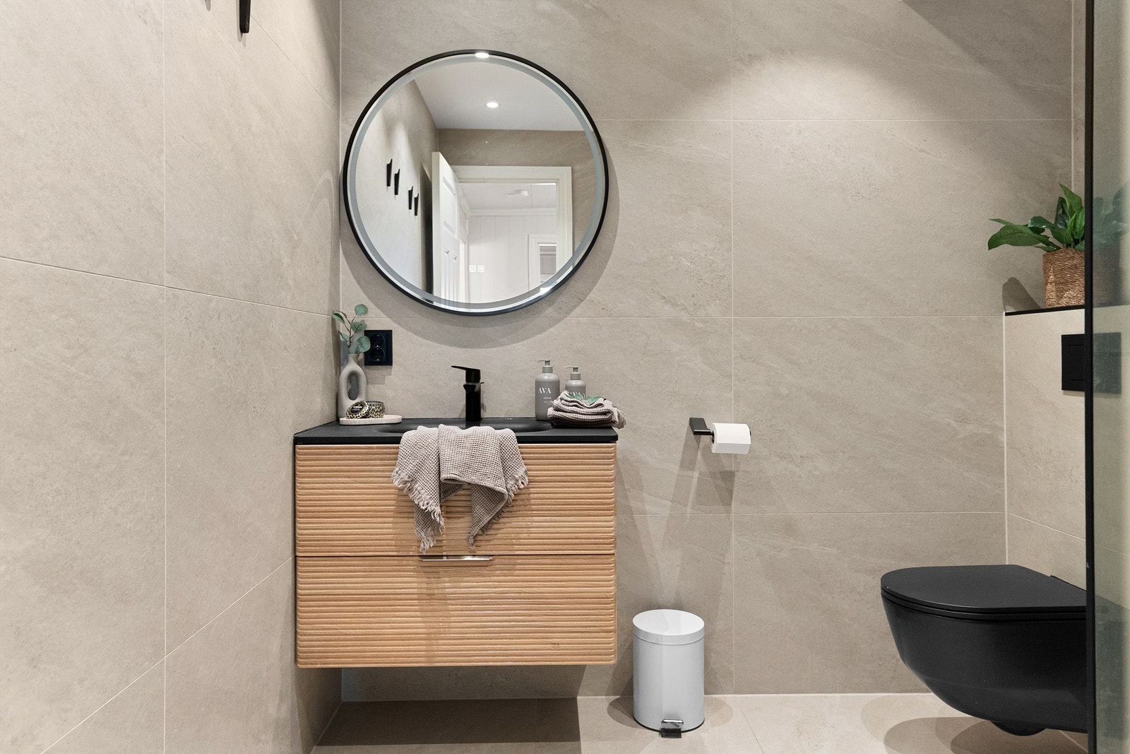 Leilighetens bad har vegghengt toalett og moderne svarte detaljer Galleribilde