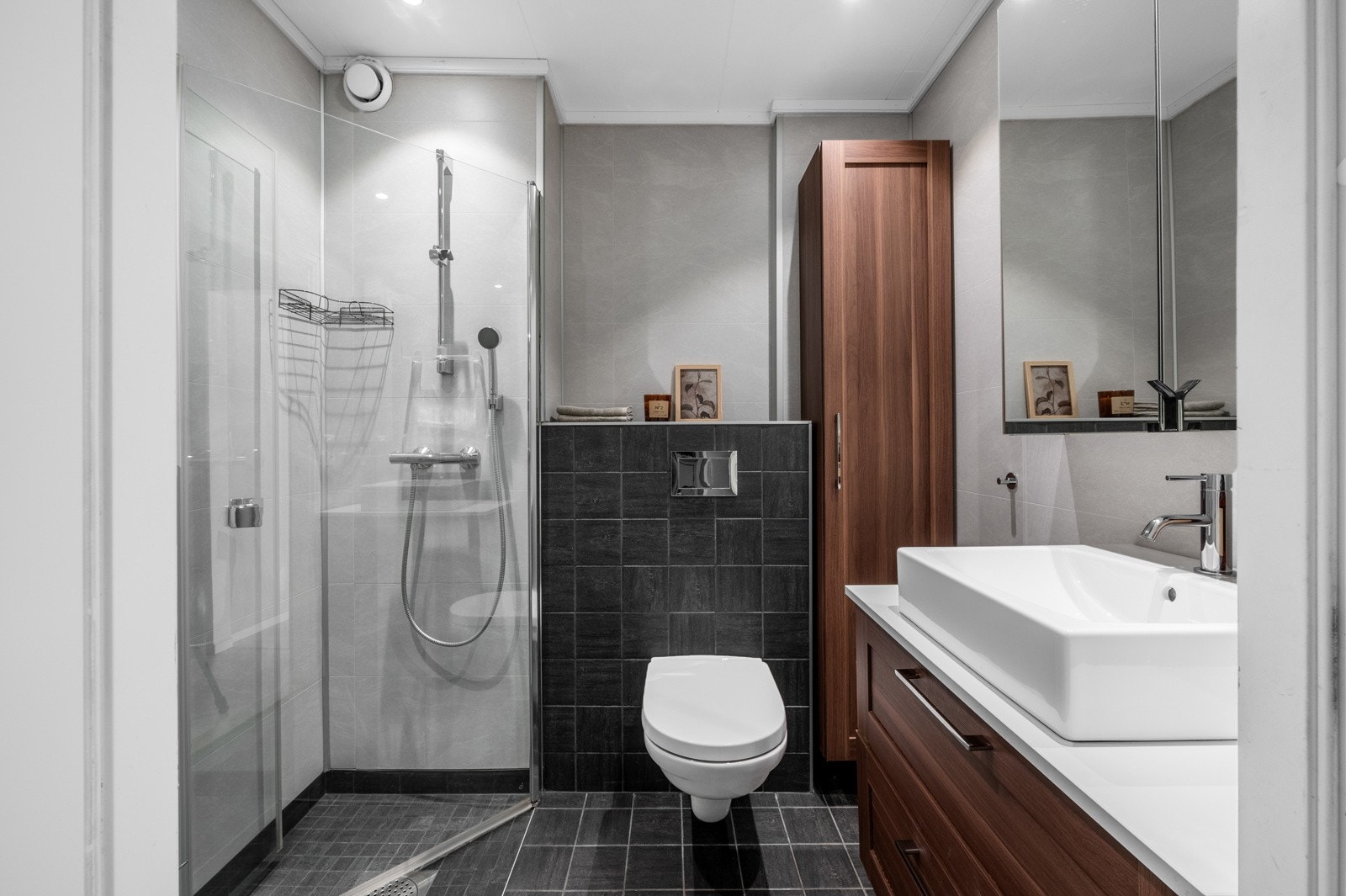 Helfliset bad med vegggmontert toalett, romslig baderomsinnredning og dusjhjørne. Galleribilde