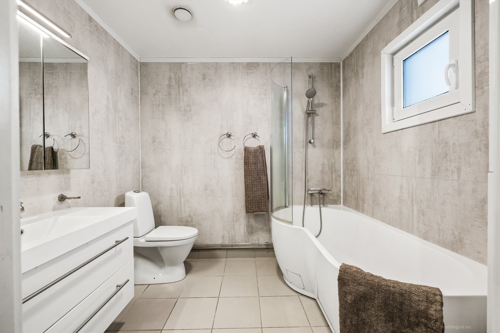 Lyst bad med baderomsinnredning, badekar og toalett Galleribilde