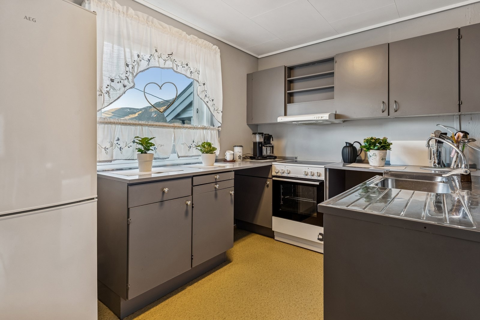 Kjøkken med eldre innredning og opplegg til vaskemaskin, komfyr og kjøl/frys Galleribilde