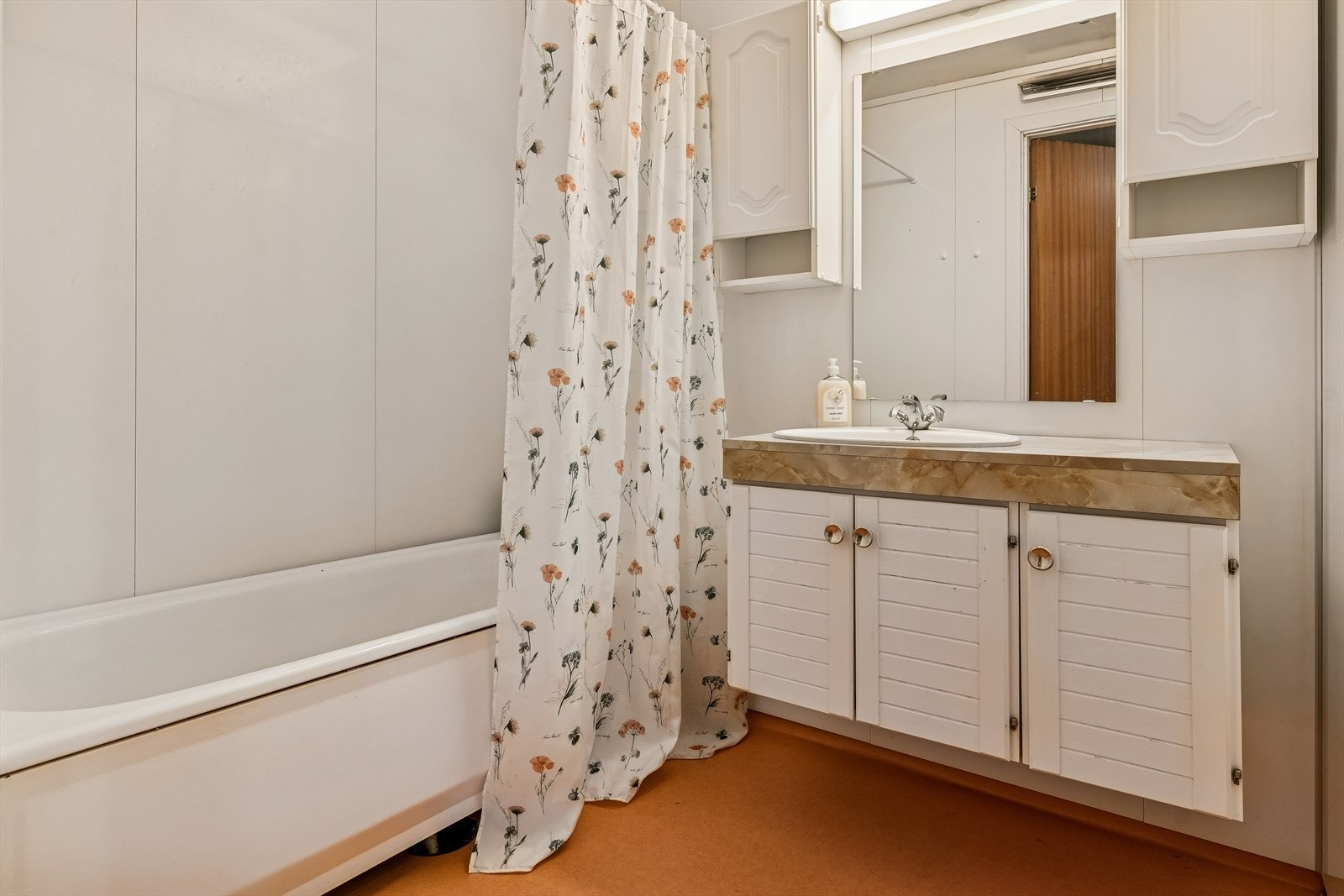 Baderom med badekar og servant med innredning. Badet er fra byggeår og har behov for renovering Galleribilde