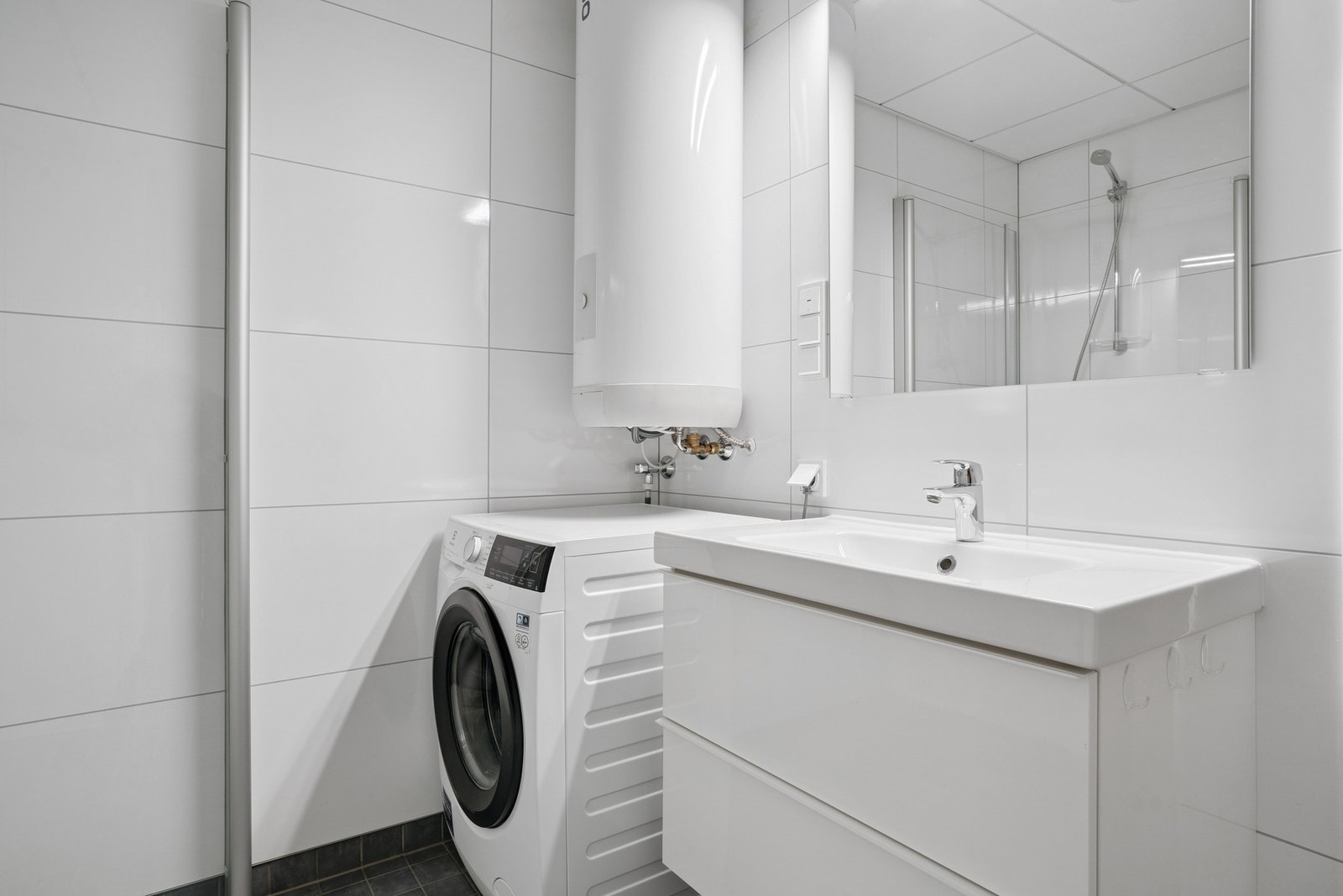 Lys baderomsinnredning, vegghengt toalett og dusjhjørnet. Galleribilde