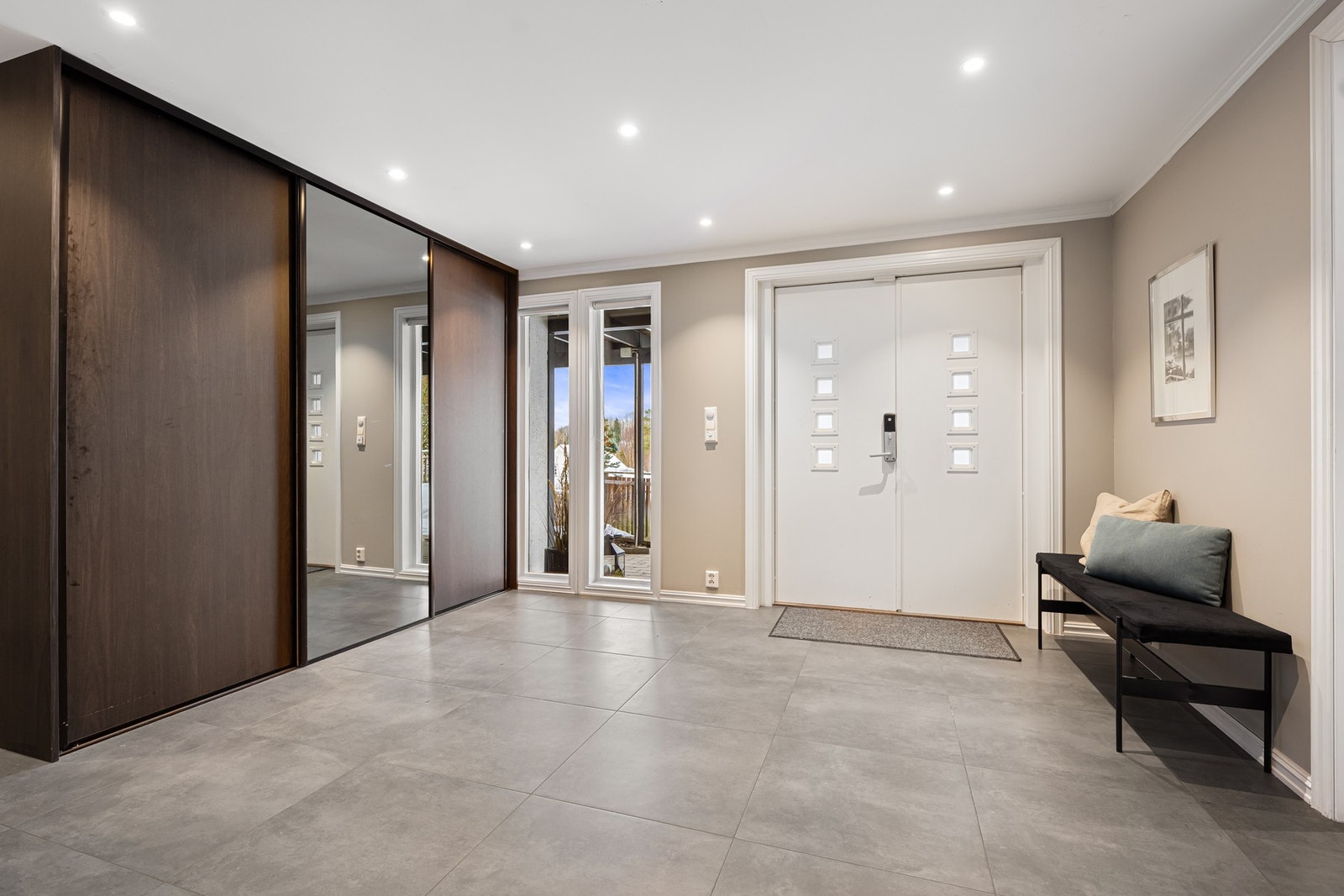 Inngangen består av doble dører, et flislagt gulv og stilrene spotter, en varm velkomst. Galleribilde