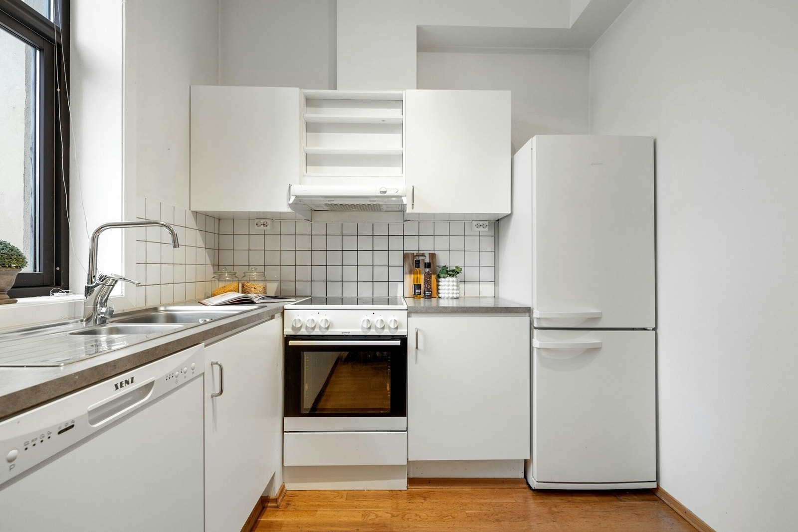 Kjøkkeninnredningen har glatte, hvite fronter og laminat benkeplate Galleribilde