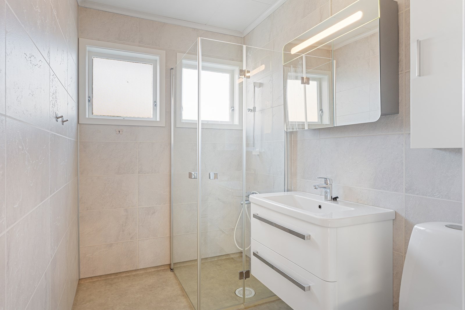 Badet i 1. etasje er pusset opp i 2015 og har baderomsplater på veggene samt belegg på gulvet - Galleribilde