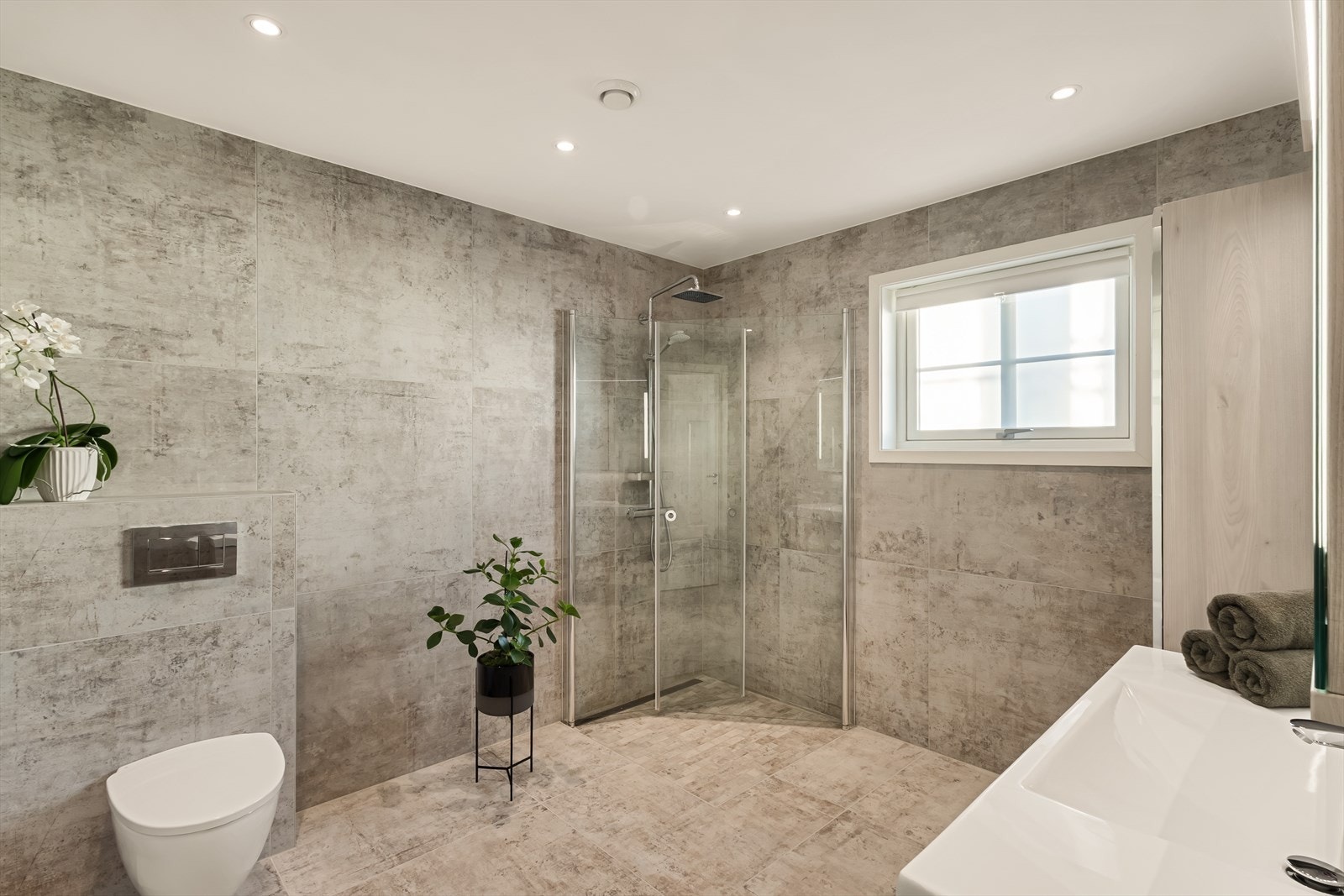 Badet er utstyrt med servant med møblement, speil med belysning, vegghengt toalett samt dusjhjørne med dusjgarnityr. Galleribilde