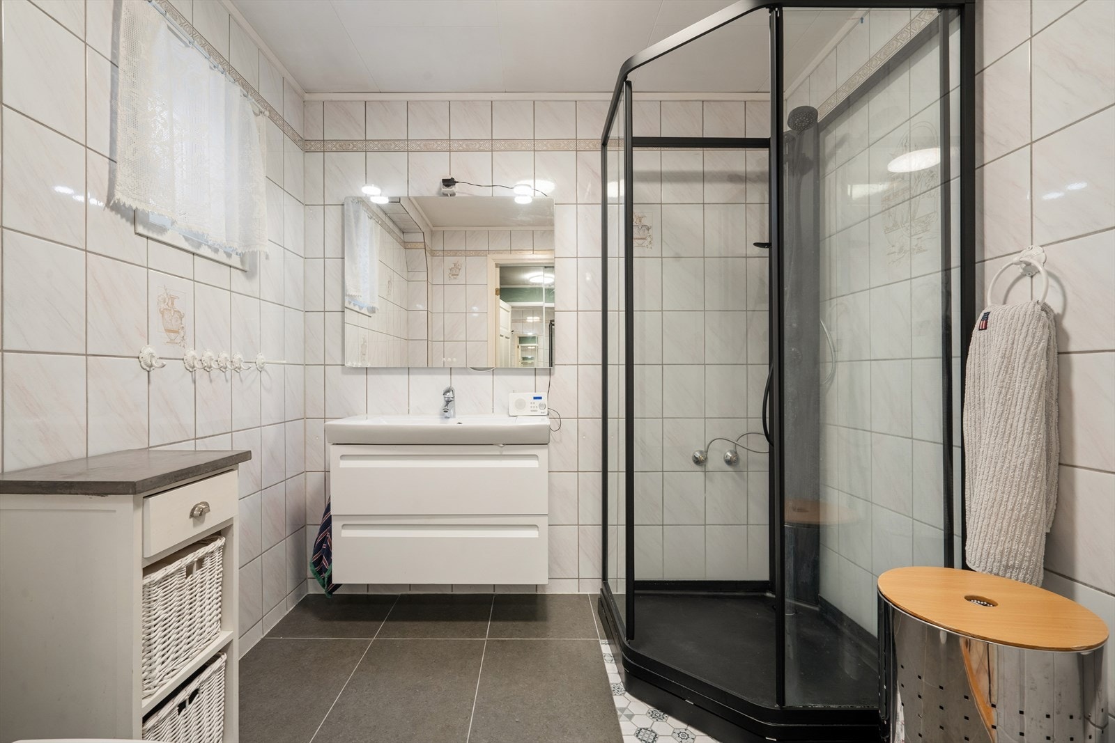 I tilknytning til entréen finnes det første av boligens bad. Badet er fra byggeår med oppgradert servant, speil og dusjkabinett, samt nye fliser på gulv Galleribilde