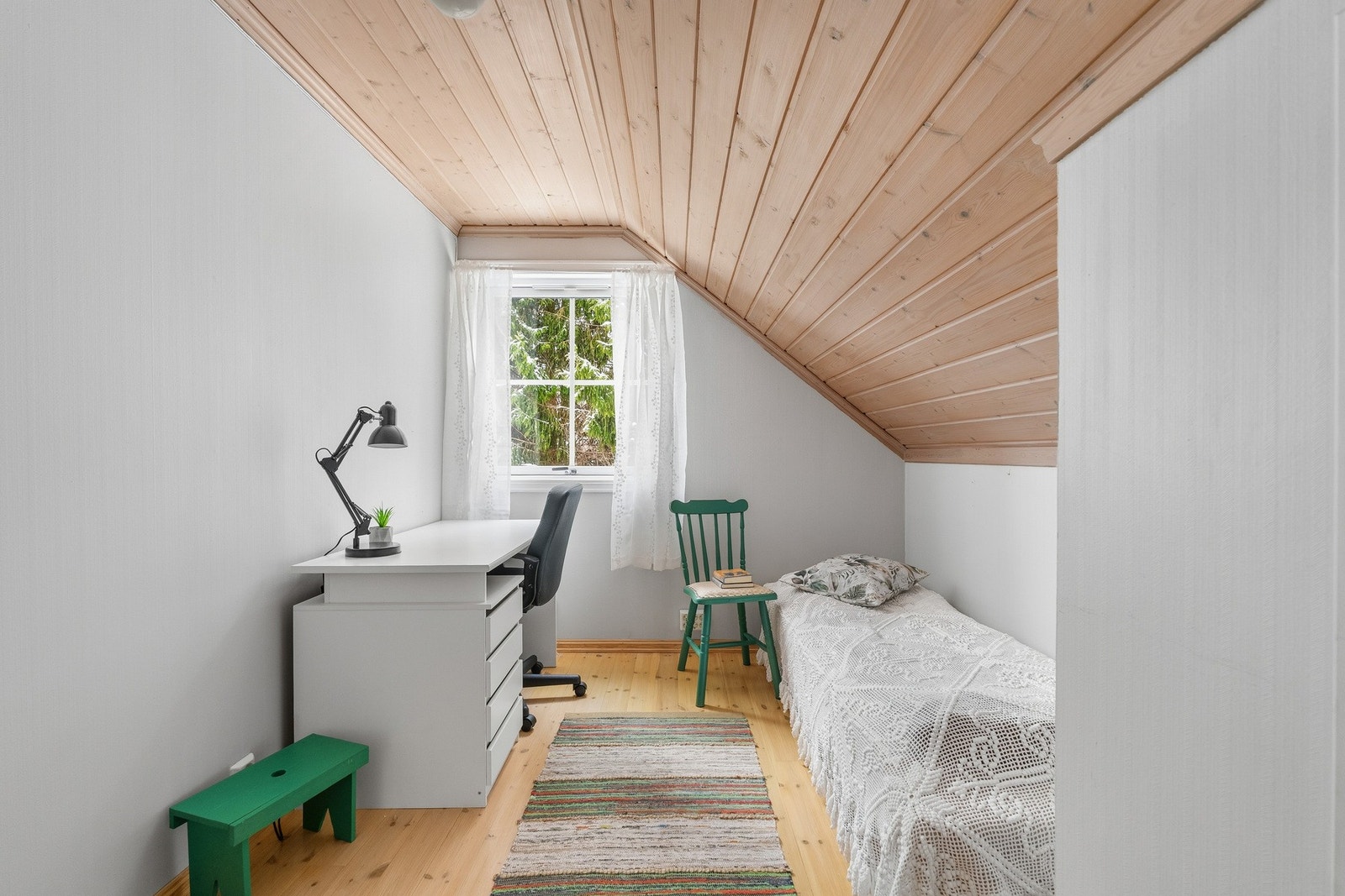 Soverom 2 har malte veggflater, sjarmerende skråtak og inngang til praktisk kneloft. Galleribilde