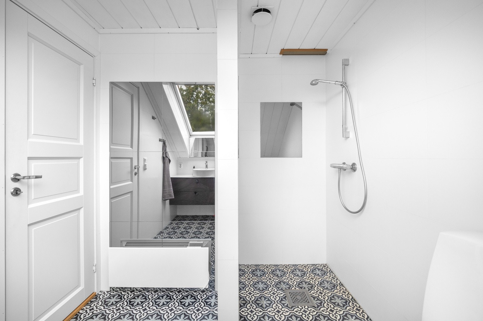 Badet har stilige gulvfliser, malte veggflater og dusjnisje med hånddusj montert på vegg. Galleribilde