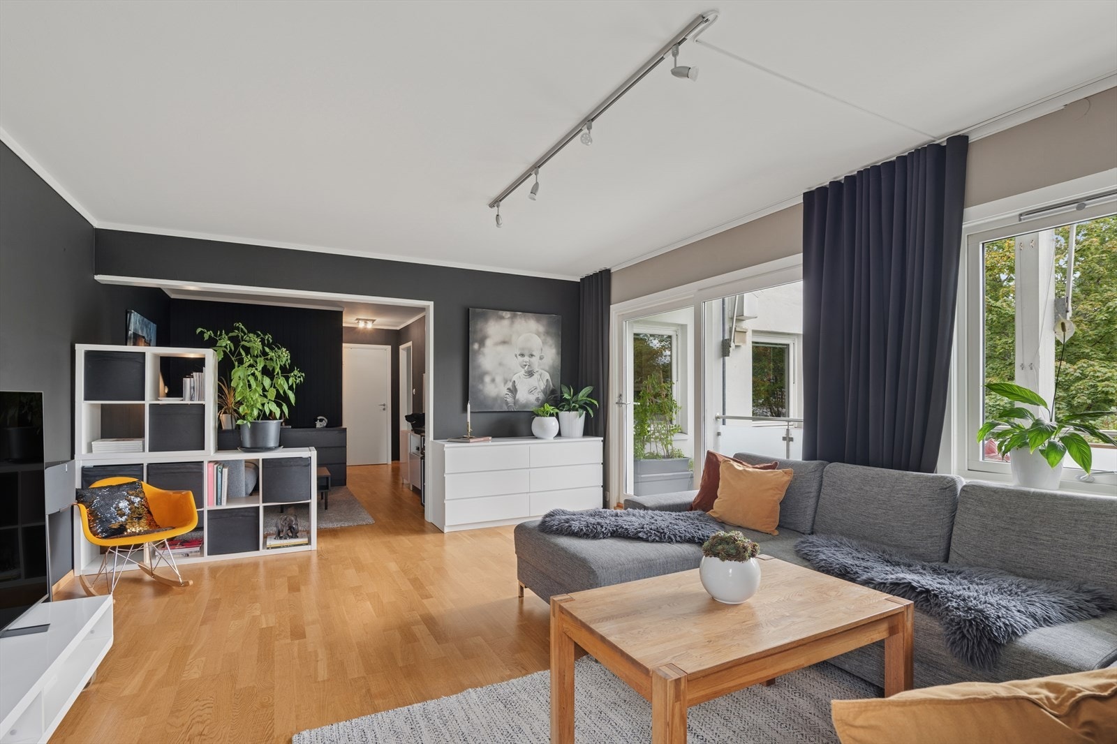 Leilighetens stue er naturlig delt inn i to soner - en koselig tv-stue og en sosial sone med mye naturlig lys fra store vindusflater Galleribilde