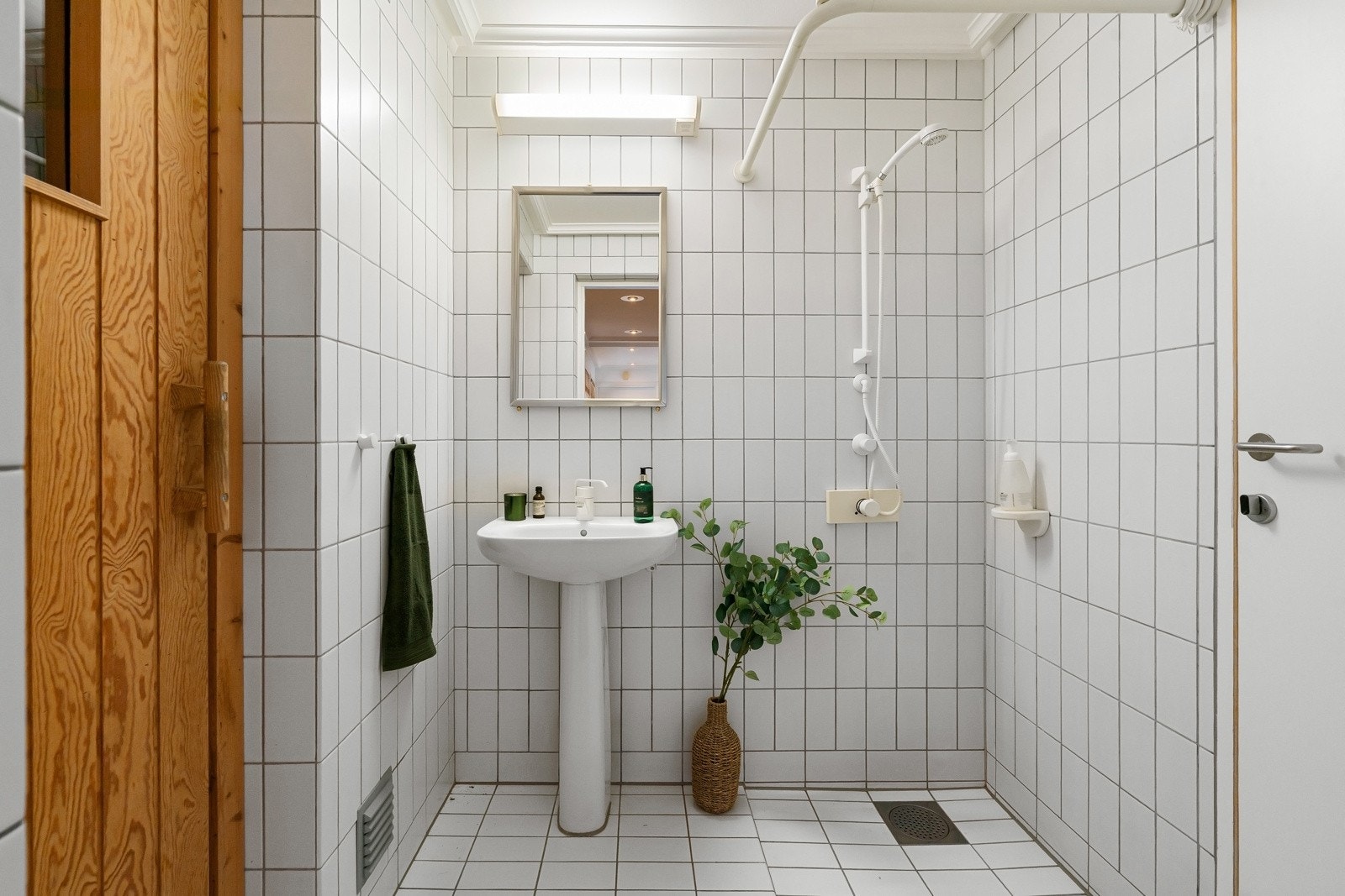 Dusjbadet i underetasjen ligger tilknyttet badstuen og har hvite, keramiske fliser på gulv- og veggflater og malt glassfiberstrie i himling. Galleribilde