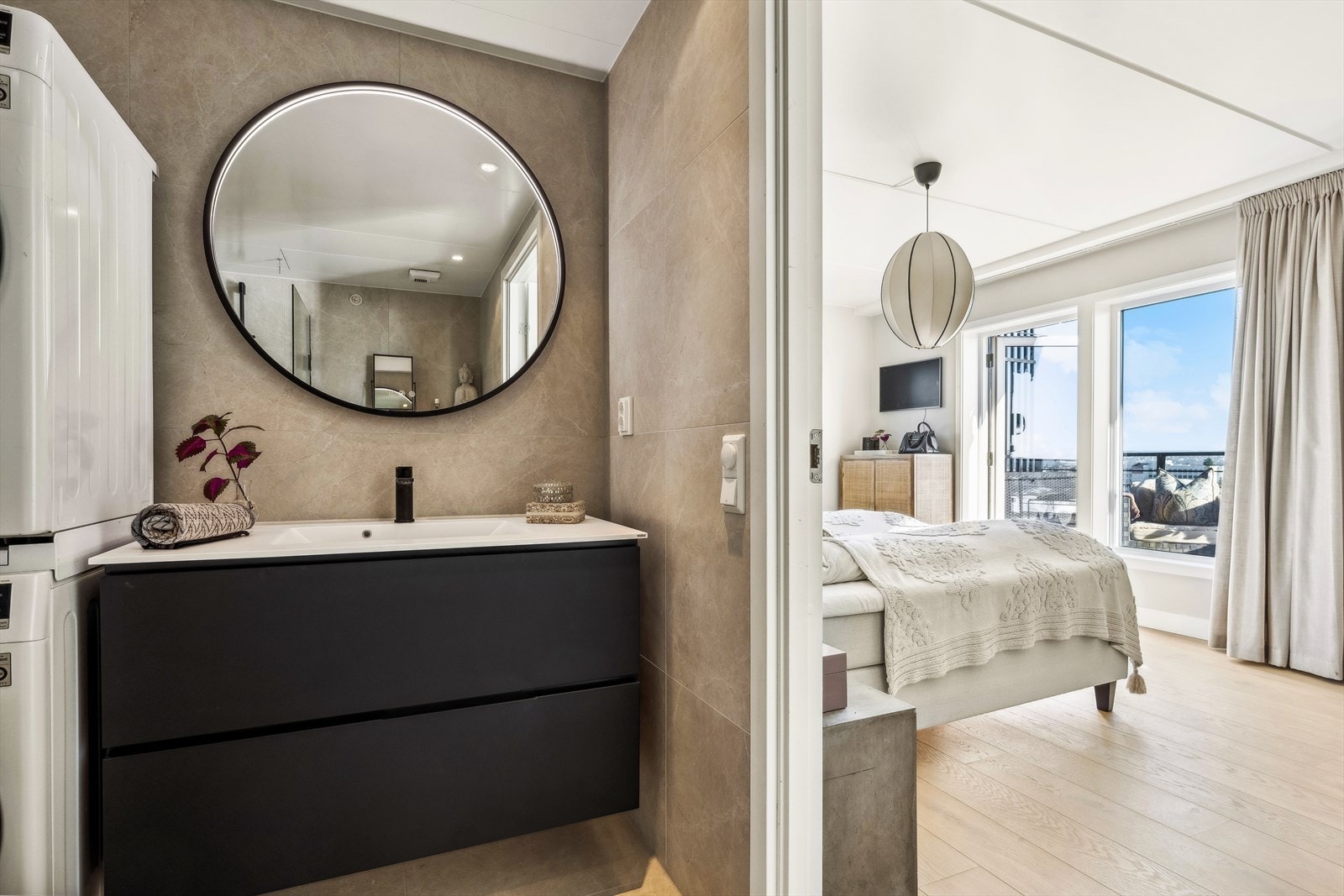 Innenfor hovedsoverommet ligger delikat flislagt baderom innredet med badekar med dusjmulighet, vask i seksjon, speil med belysning, vegghengt toalett og opplegg for vaskemaskin og tørketrommel Galleribilde