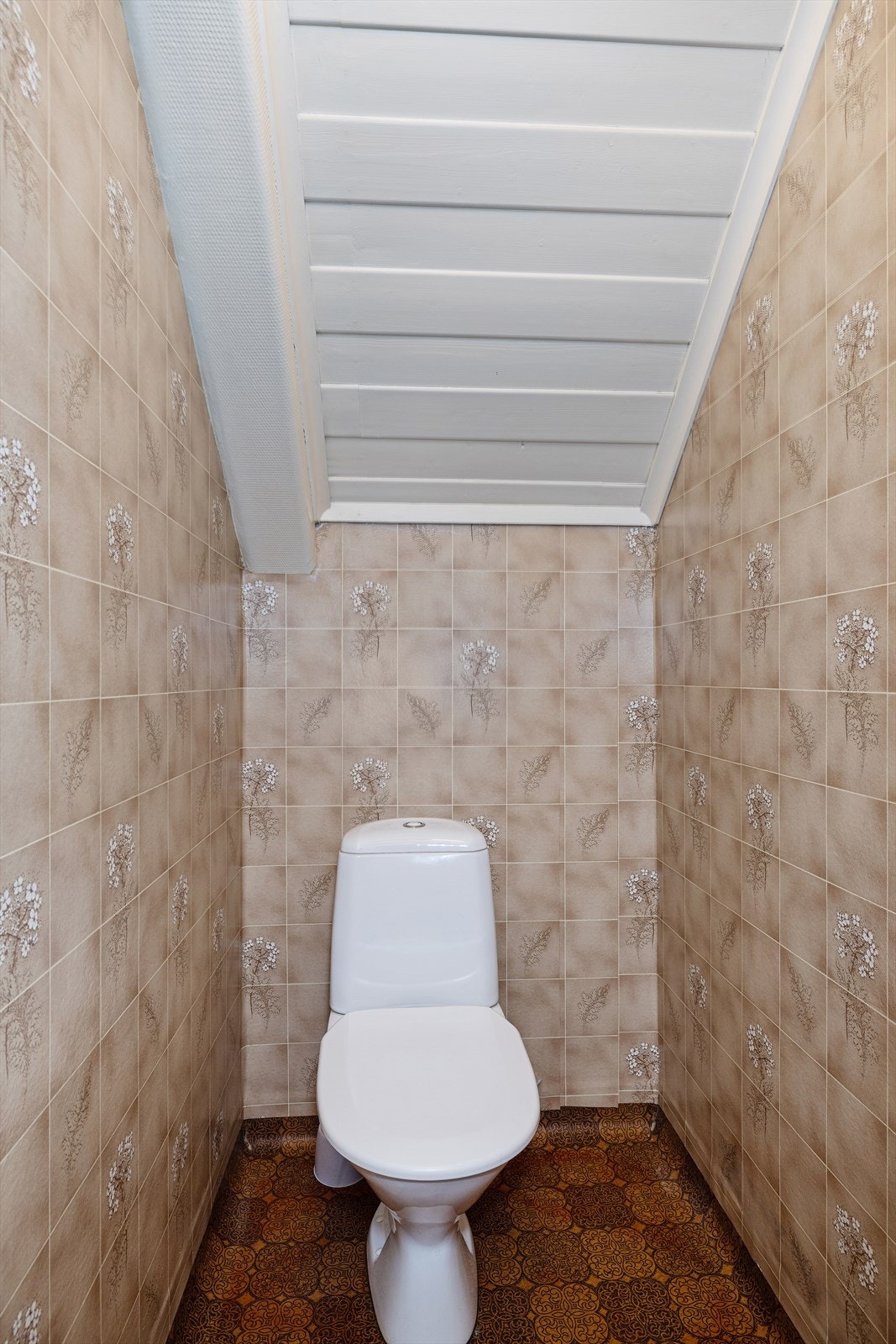 Et separat toalettrom med vinylgulv og våtromstapet. Galleribilde