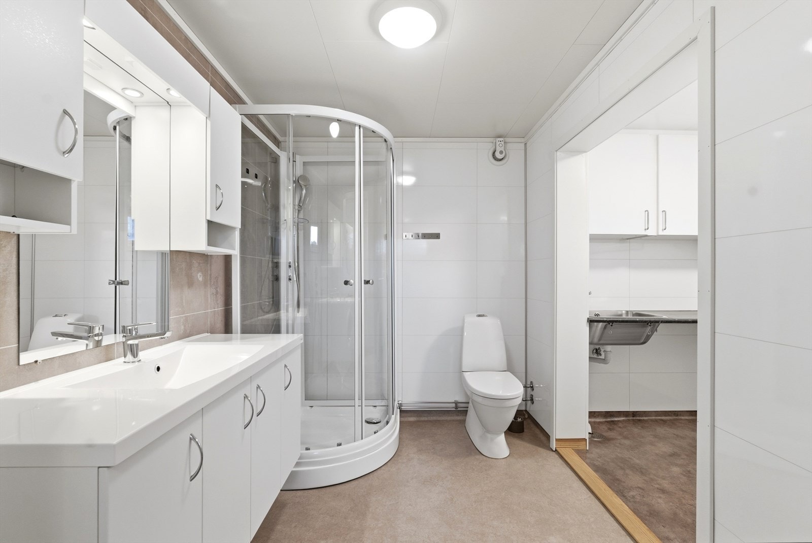 Badet er utstyrt med dusjkabinett, gulvstående toalett og en lys og romslig baderomsinnredning. Galleribilde