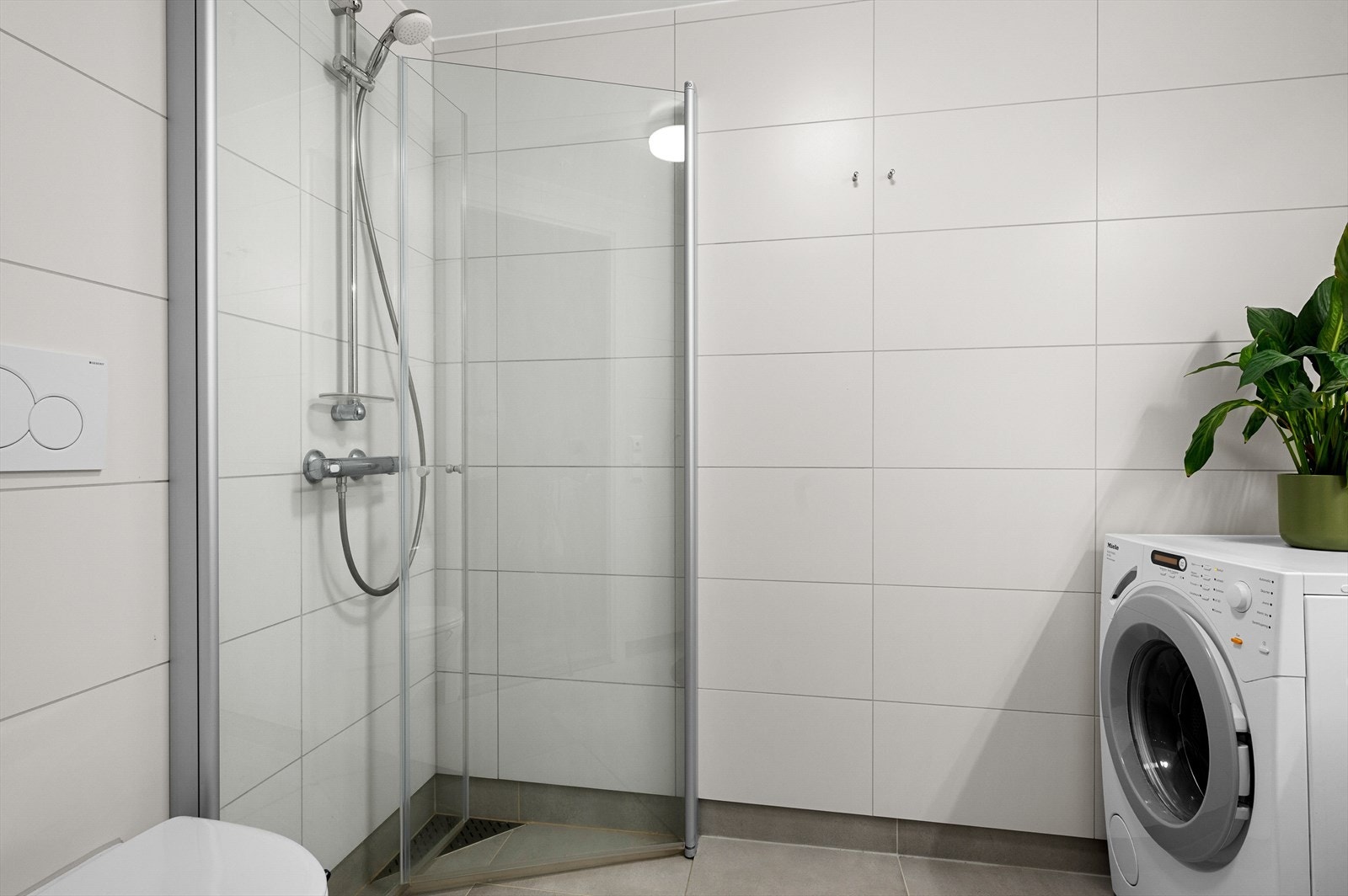 Badet er utstyrt med vegghengt toalett, hjørnedusj, baderomsinnredning og opplegg for vaskemaskin. Galleribilde