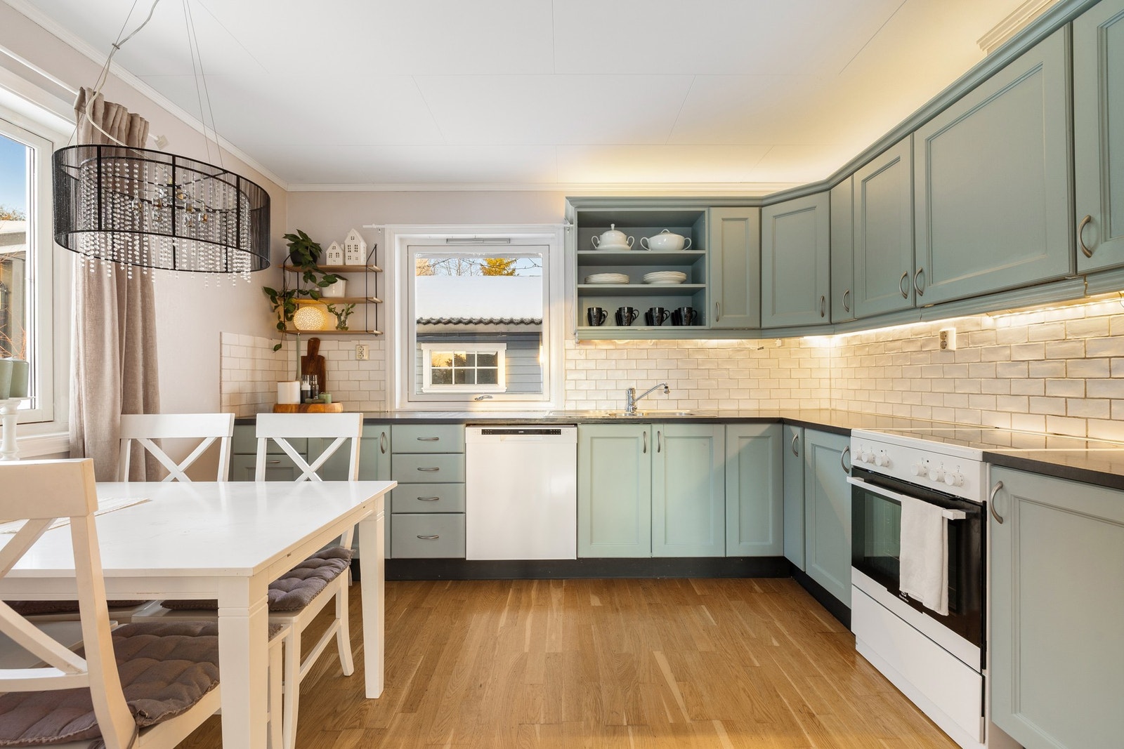 Innbydende kjøkken med plass til et stort spisebord og dekorative flis på veggen. Galleribilde