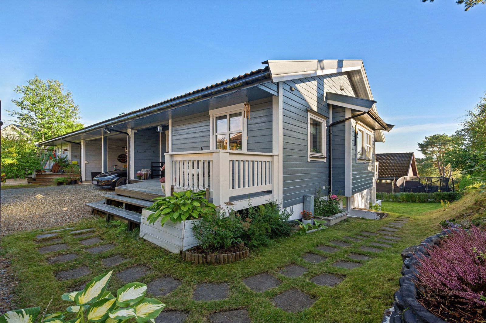 Tomten er gjennomført pent opparbeidet med beplantning av busker, trær og blomsterbed, samt en hellelagt sti. Galleribilde