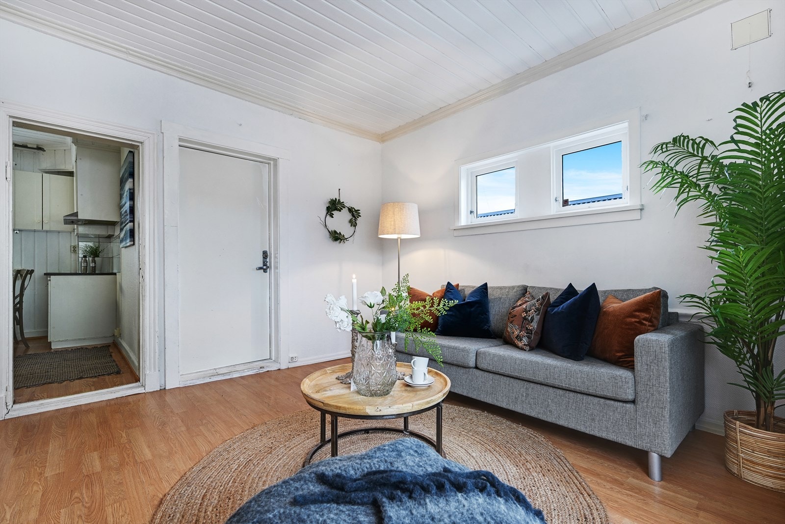 Stue med inngangsdør til leiligheten og kjøkken i bakgrunnen. Galleribilde