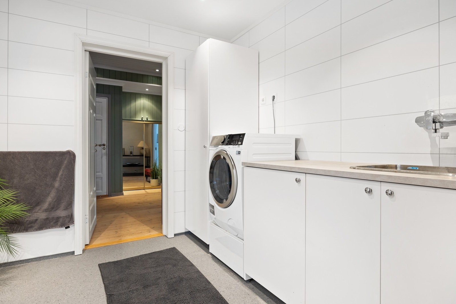 Vaskerom/bad innredet med dusjnisje, servant med servantskap, klosett og skapinnredning med benk og avsatt plass for vaskemaskin. Galleribilde