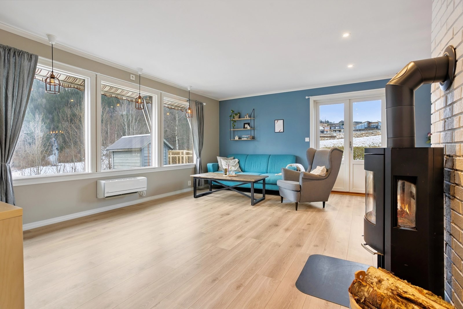 Romslig stue med spotlights i tak og vedovn Galleribilde