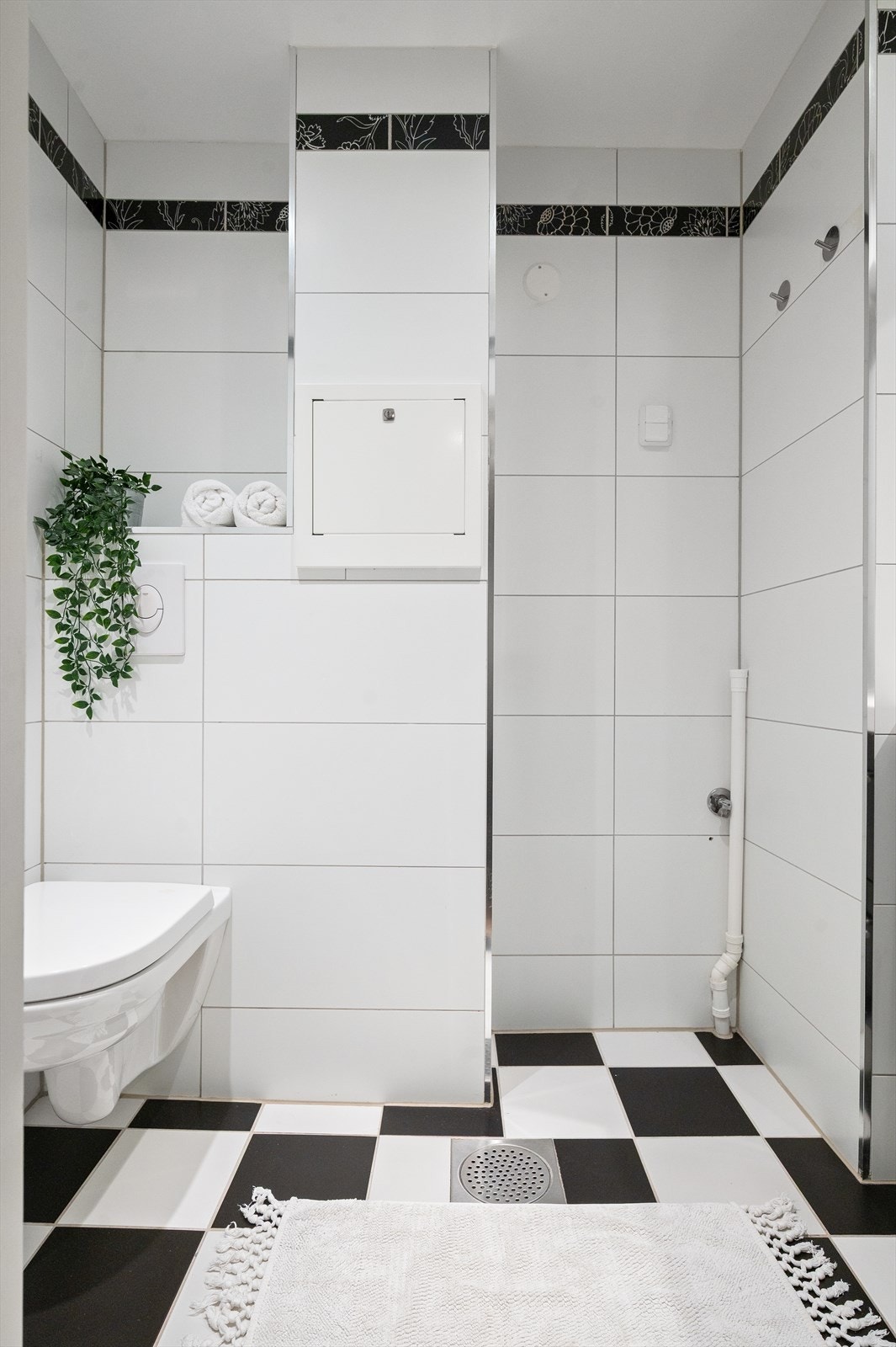 Pent og funksjonelt baderom innredet med vegghengt toalett, servant med innredning, speil og dusjnisje med forheng. Galleribilde