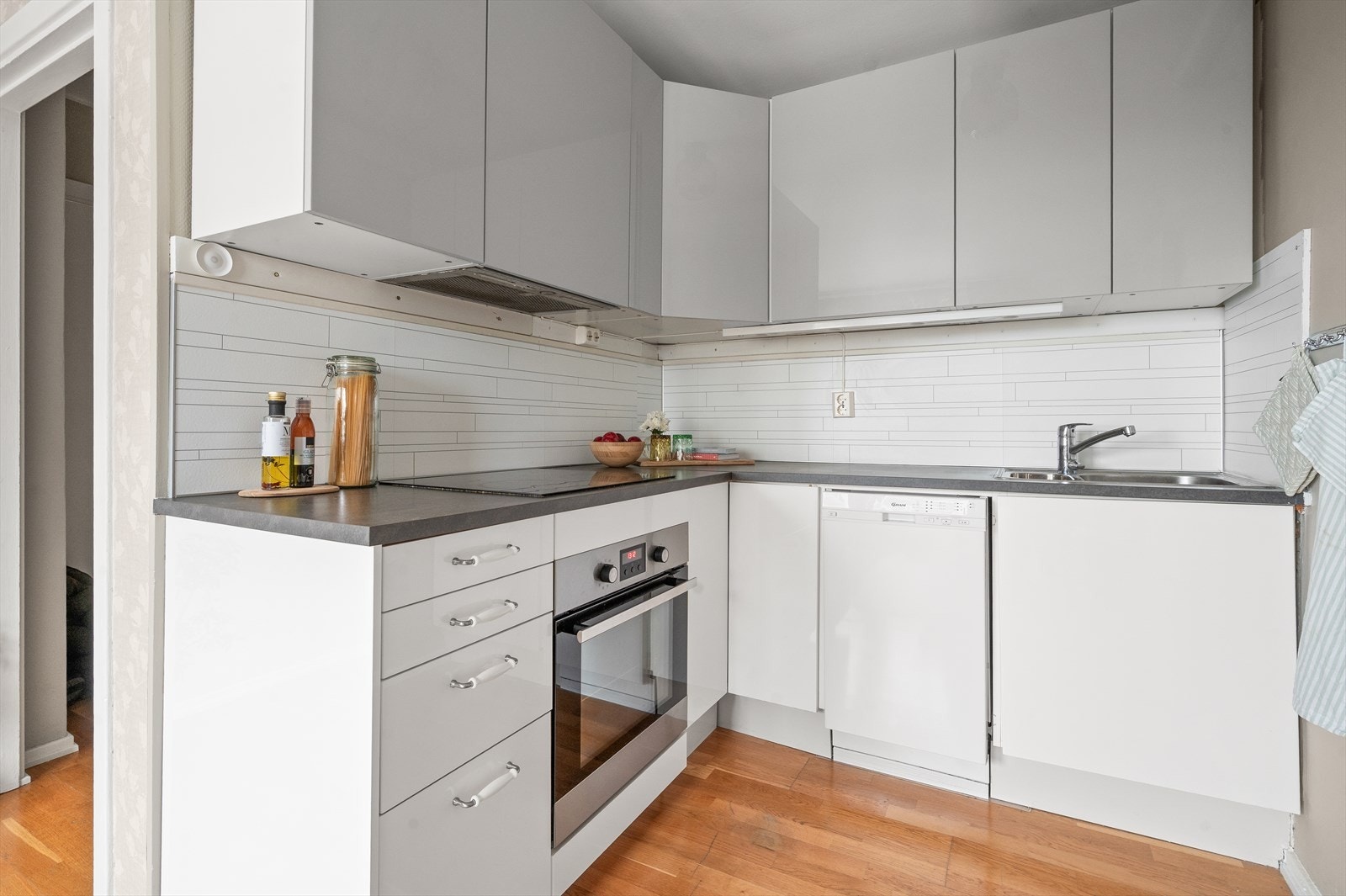 Integrerte hvitevarer bestående av platetopp, stekeovn og oppvaskmaskin. Over kokeplass er det kullfilterventilator. Galleribilde