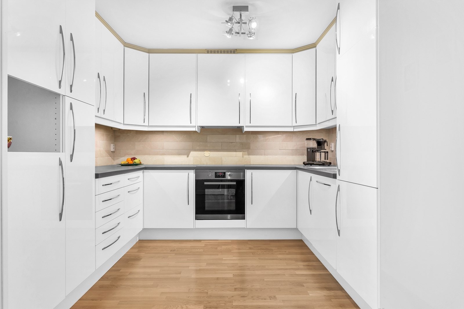 Kjøkkeninnredning med høyglansede fronter og integrerte hvitevarer. Galleribilde