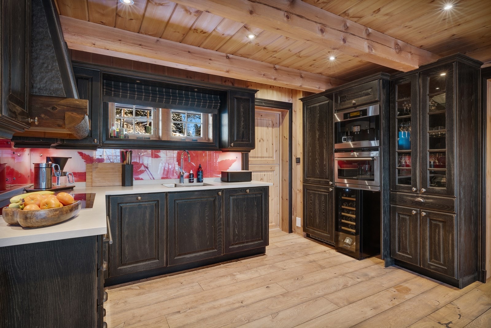 Klassisk kjøkkeninnredning med profilerte fronter/vitrineskap, benkeplate i dektonstein, underlimt silgranitt vask, glassplater over benkeplate og belysning under overskap. Galleribilde