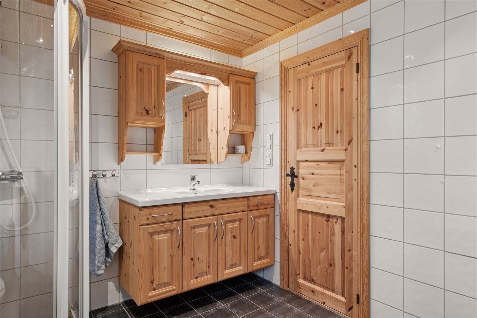 Med servantinnredning, toalett, dusjhjørne og opplegg for vaskemaskin, er badet godt tilrettelagt for lengre opphold. Rikelig med oppbevaringsplass gjør det enkelt å la nødvendigheter bli igjen på hytta. Galleribilde