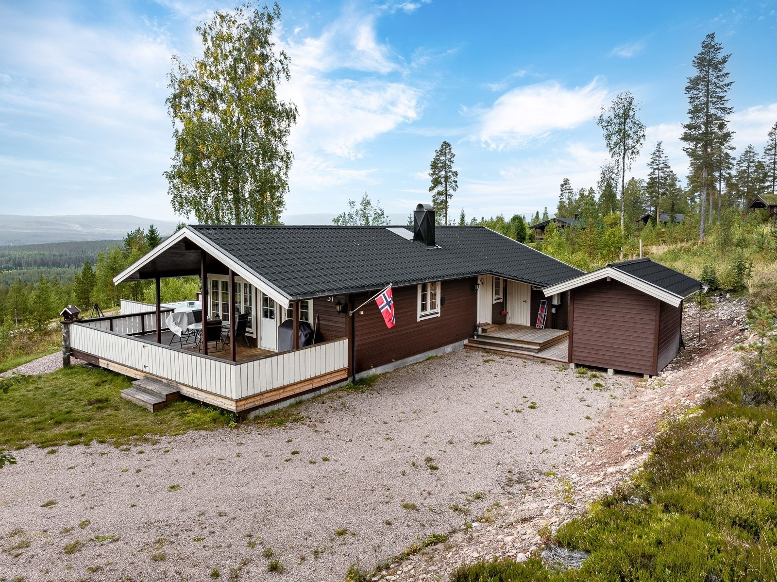 Adkomst via et delvis overbygget inngangsparti med en terrasse på ca. 12m², samt tilknytning til bod og frittstående uthus. Hytta er jevnlig vedlikeholdt med bla. ny taktekking og pipetopp montert i 2025. Galleribilde