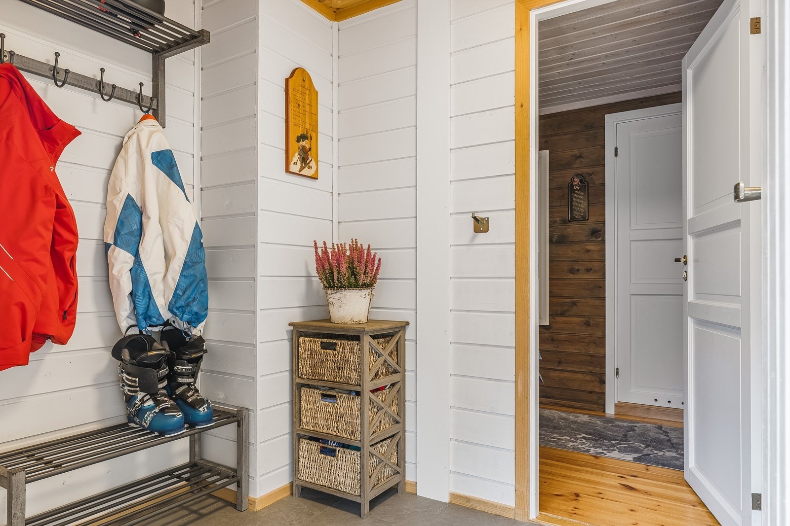 Entréen har flislagt gulv, lysmalt panel på veggene og plass til både sko og oppheng av yttertøy. Galleribilde