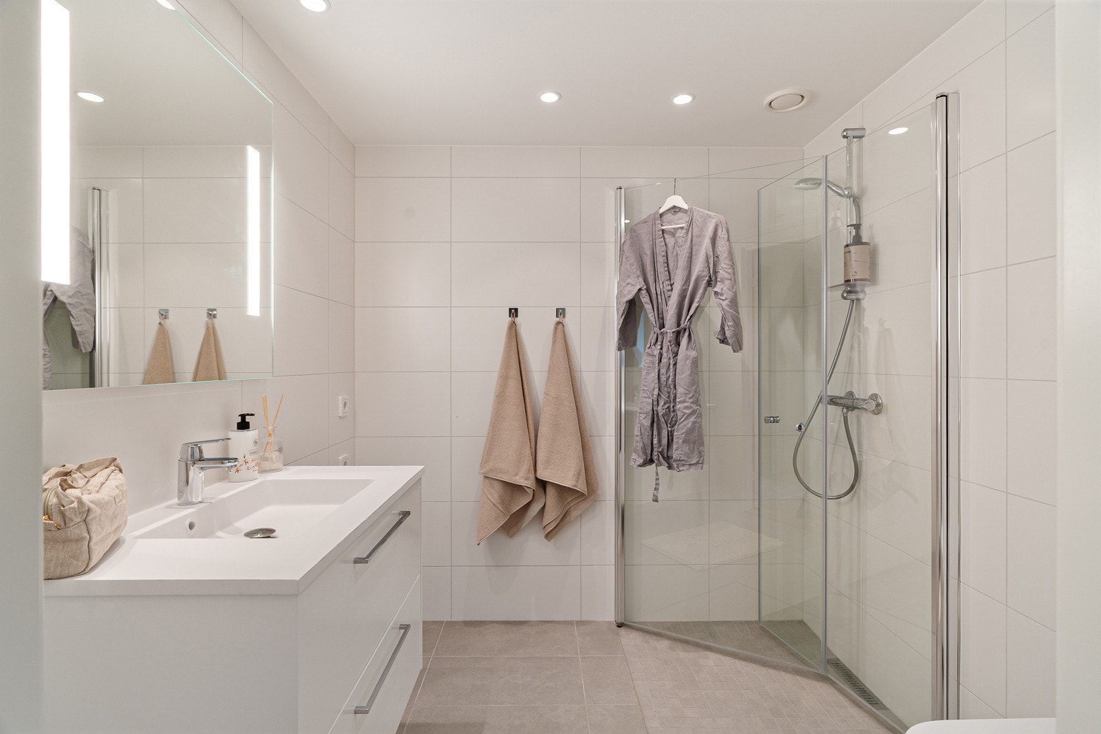 Baderommet er delikat innredet med lyse fliser på vegger og gulv, for et eksklusivt velværepreg. Det hele forsterkes av velplasserte downlights i himling. Galleribilde