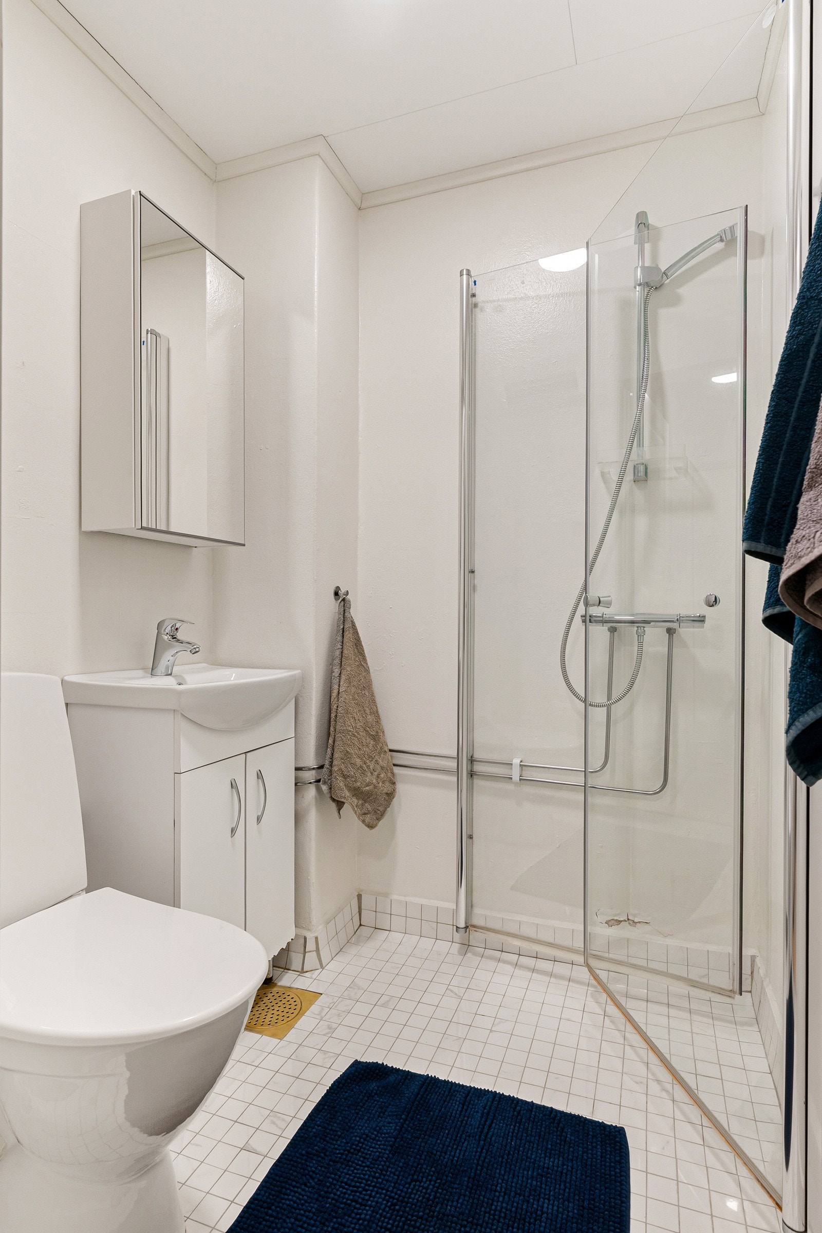 Badet er utstyrt med servantinnredning med speil, toalett og dusjhjørne med innfellbare glassdører. Galleribilde