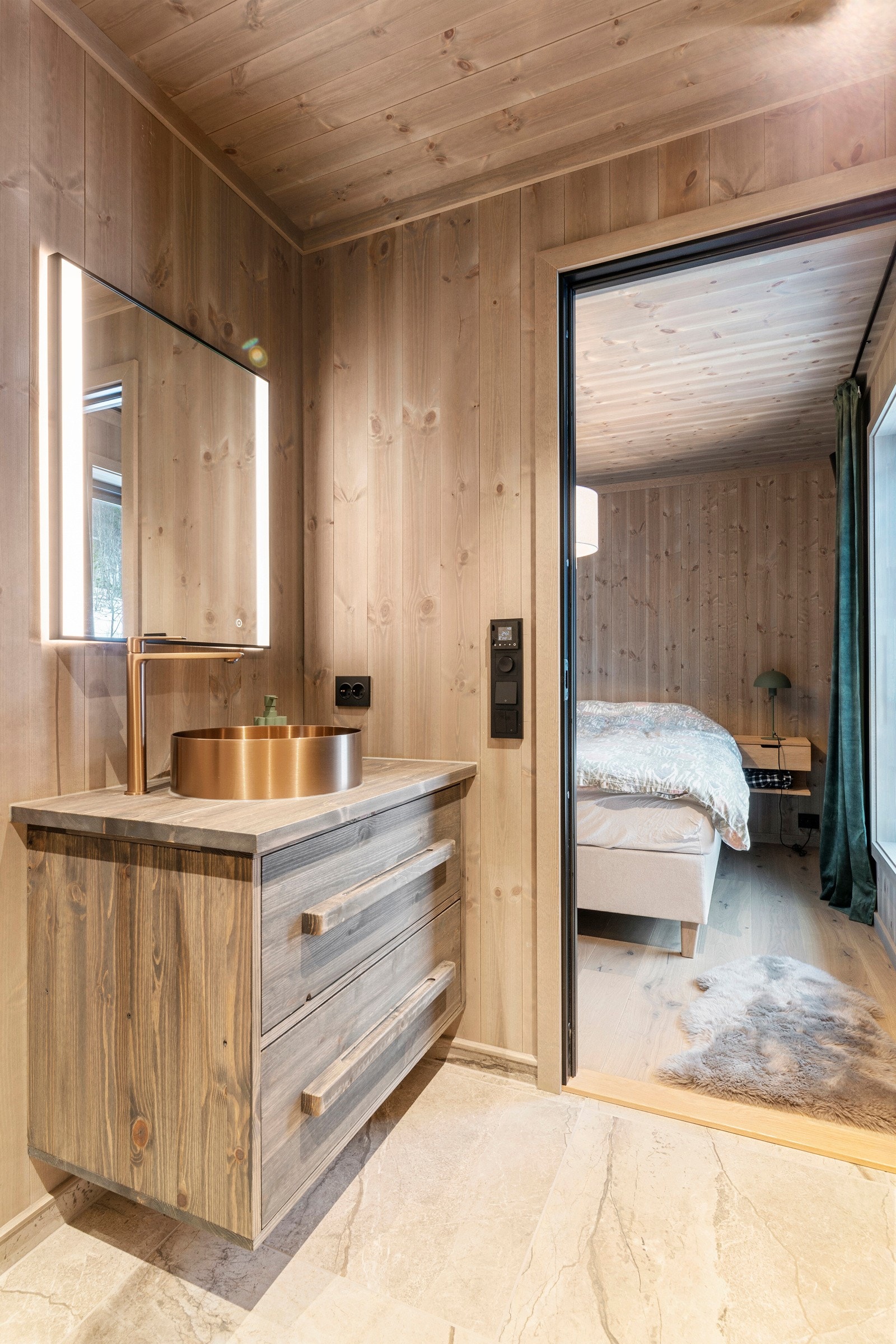 Pen innredning med overliggende servant. Det er gjennomgående med sorte detaljer på armatur og kontaker. Galleribilde