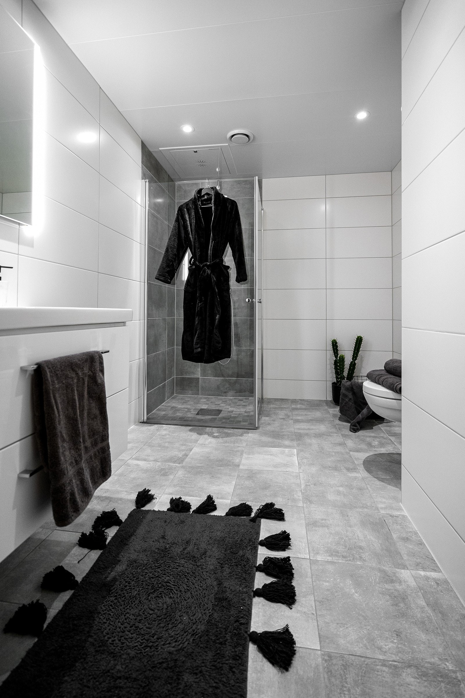 Delikat bad innredet med toalett, dusjhjørne, servantinnredning og opplegg for vaskemaskin. Galleribilde