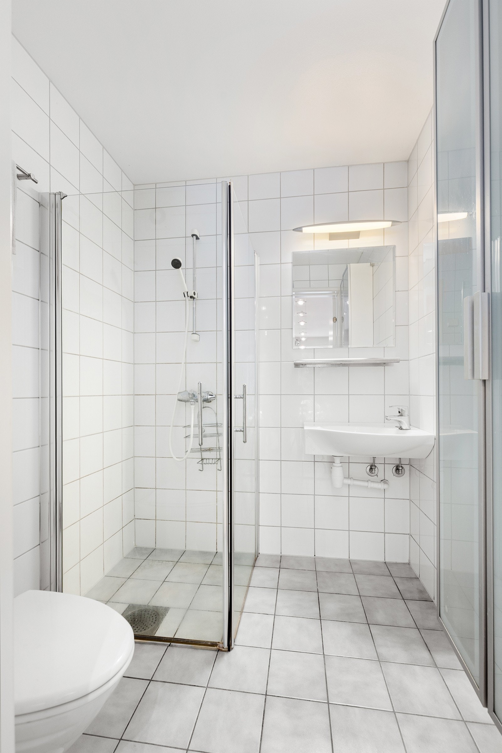 Badet er innredet med frittstående servant med 1-greps blandebatteri, dusj med dører, gulvmontert toalett og fordelerskap til vannbåren gulvvarme. Galleribilde