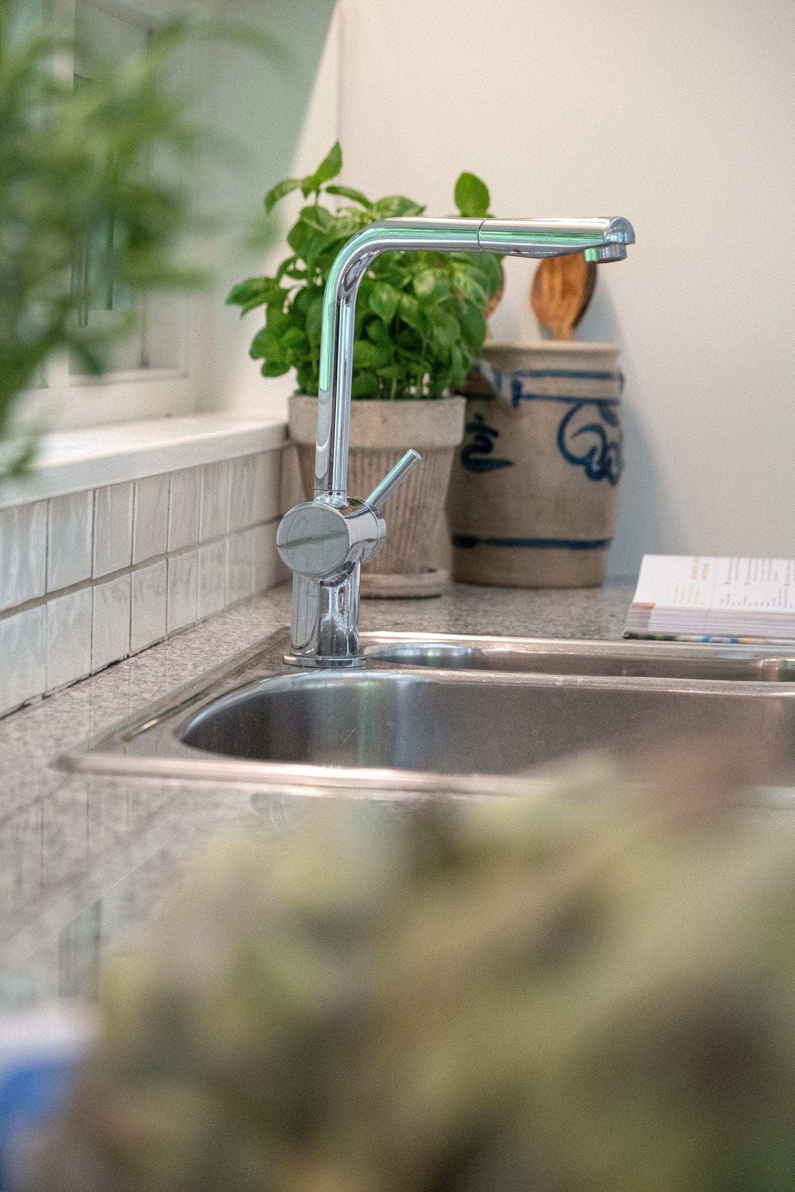 Kjøkkenet har en stilren innredning med slette fronter, benkeplate i stein og fliser på veggen over benken som gir et moderne uttrykk Galleribilde