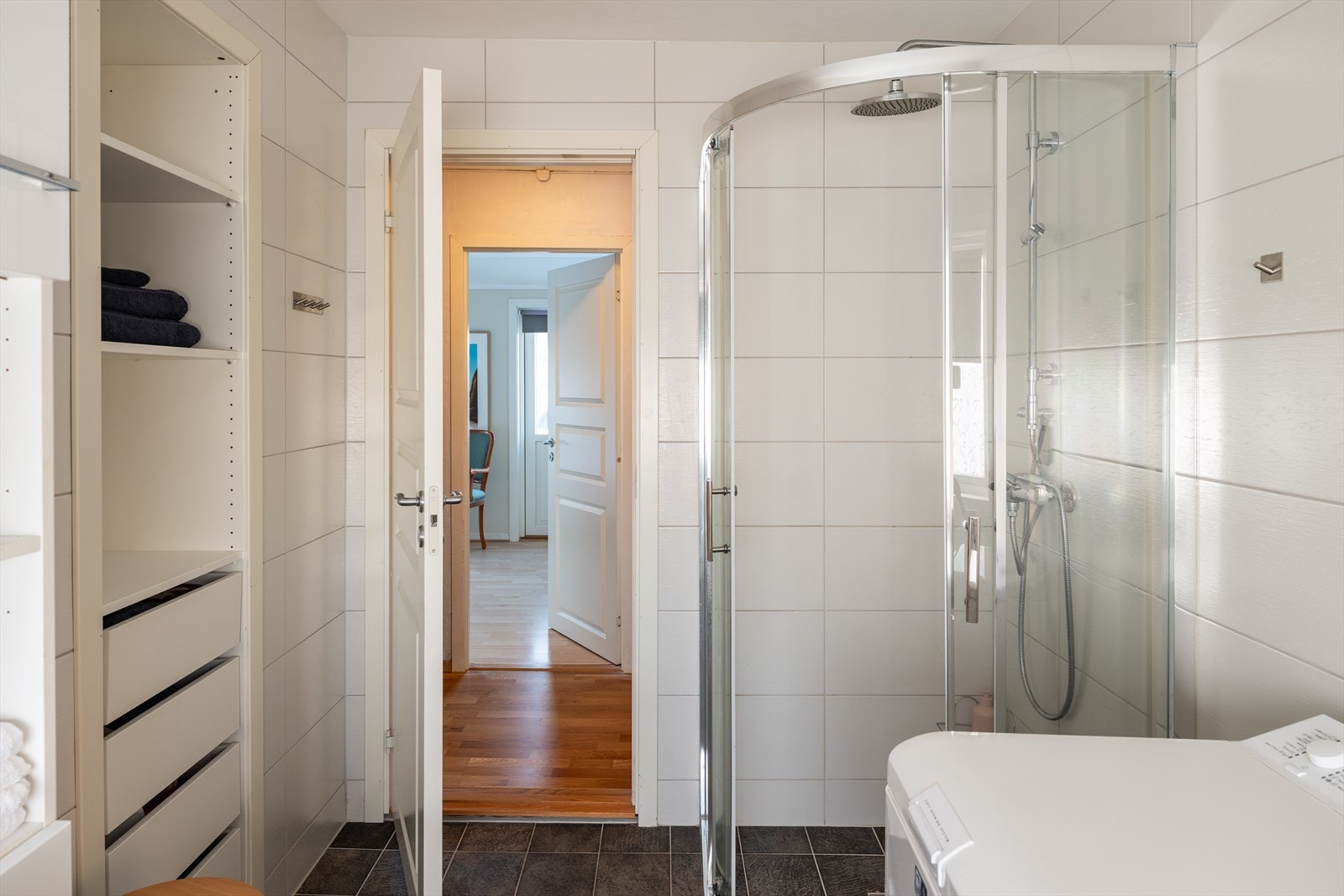 Videre er badet innredet med dusjhjørne, opplegg for vaskemaskin, servant, servantskap, wc og behagelig gulvvarme. Galleribilde