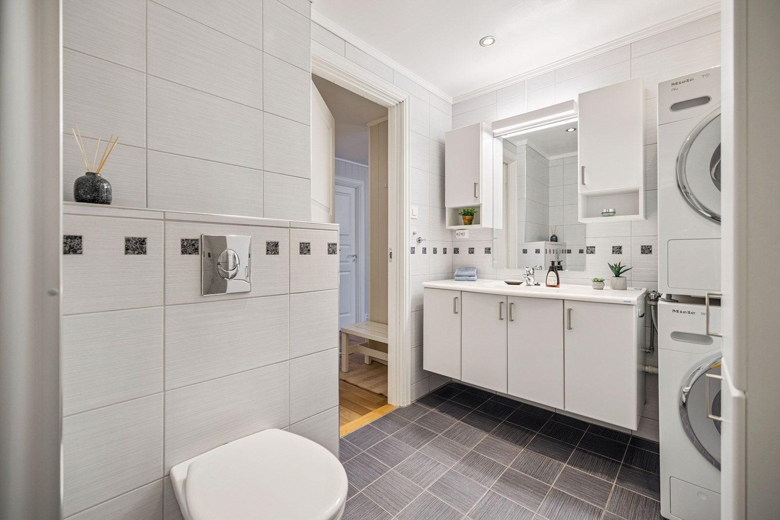 Flott flislagt bad som er utstyrt med vegghengt toalett og servant med underskap. Galleribilde