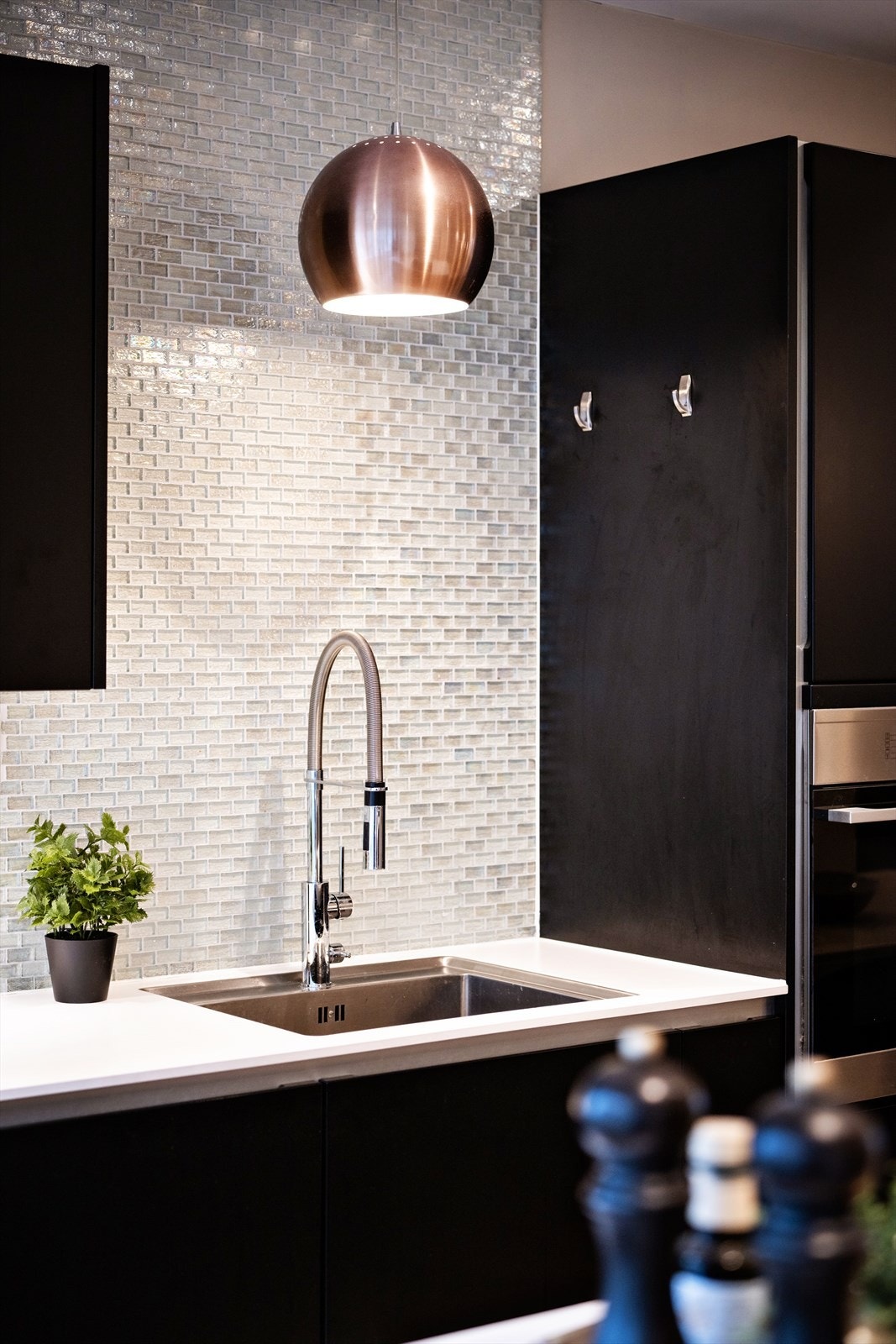 Mosaikkfliser over kjøkkenbenken gir en fin kontrast til de mørke flatene. Galleribilde