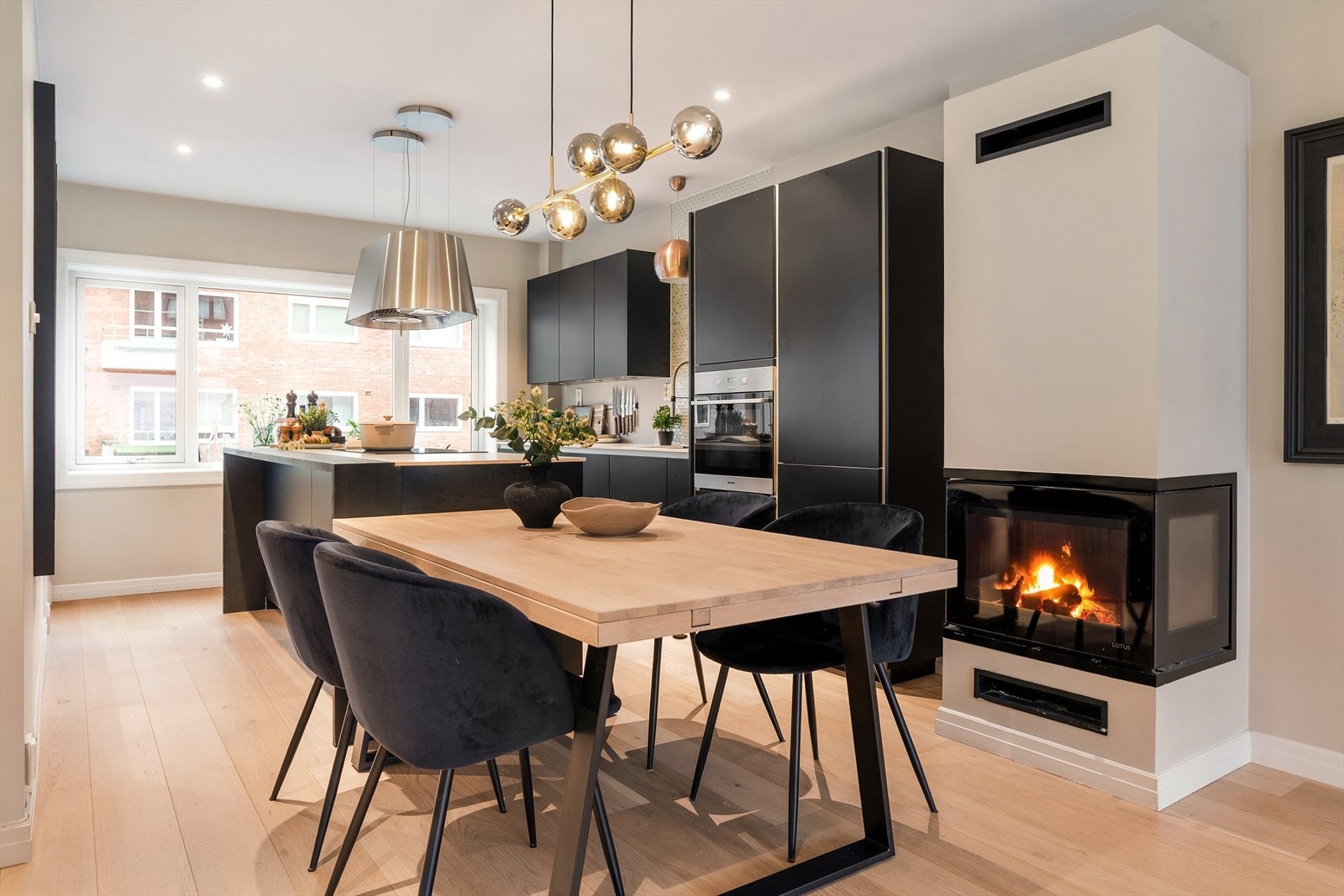 Leiligheten har en åpen stue- og kjøkkenløsning med en sentralt plassert peis. Galleribilde