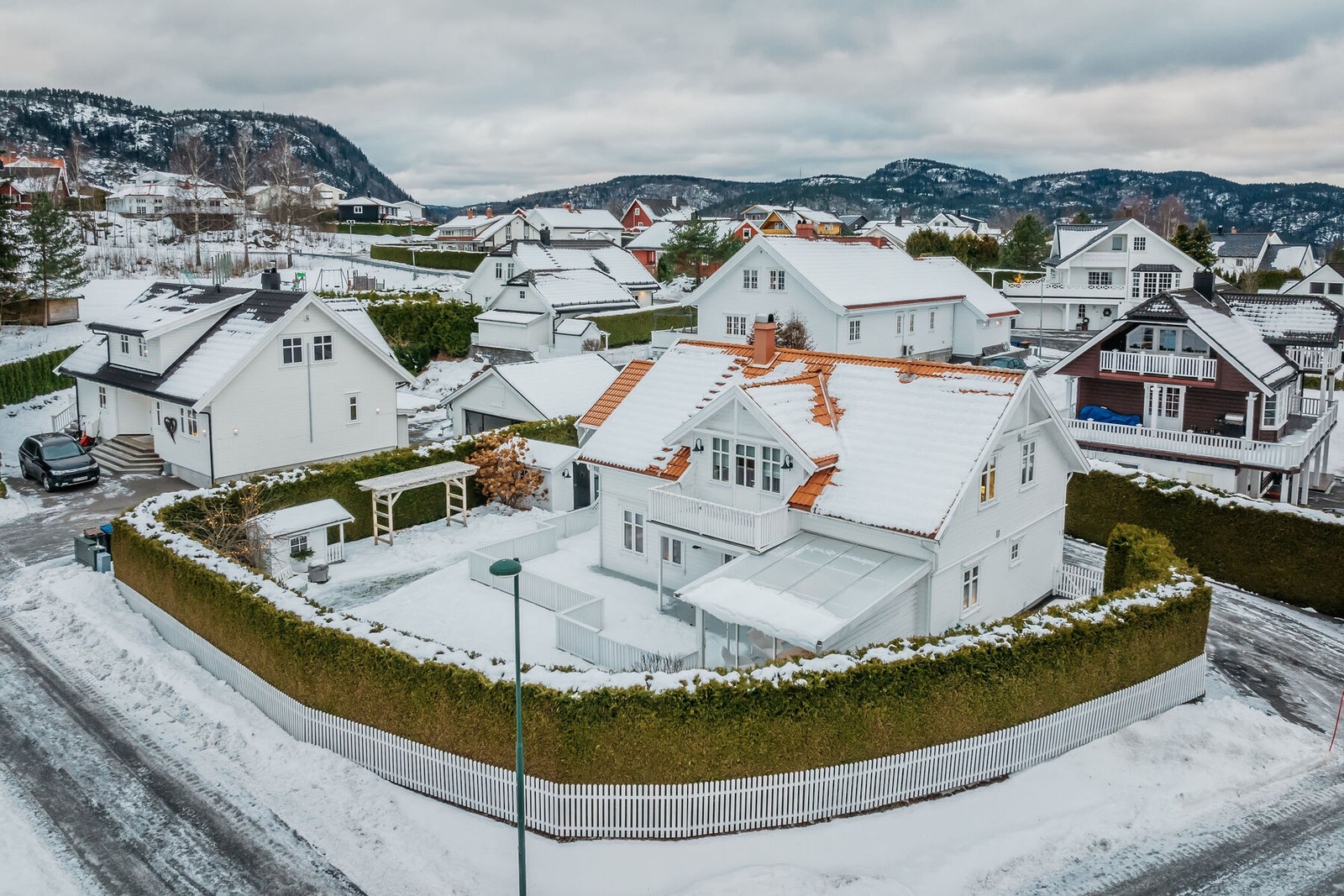 Tomten rammes fint inn av en velstelt hekk og et hvitmalt stakittgjerde. Galleribilde