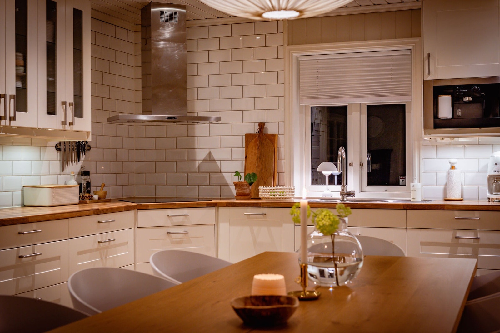 Over benken er det belysning og hvite fliser, og over kokesonen har kjøkkenet en takhengt ventilator. Downlights i taket tilfører ekstra lys til arbeidsflatene. Galleribilde