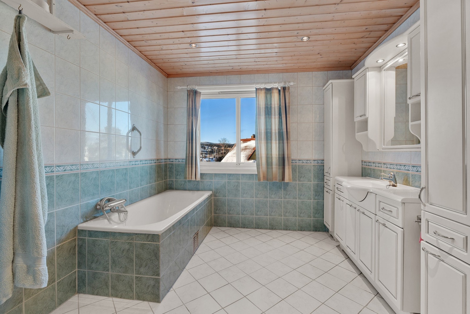 Badet er utstyrt med dusjnisje med skyvefelt, innfliset badekar, gulvstående klosett og servant i helstøpt plate. Galleribilde