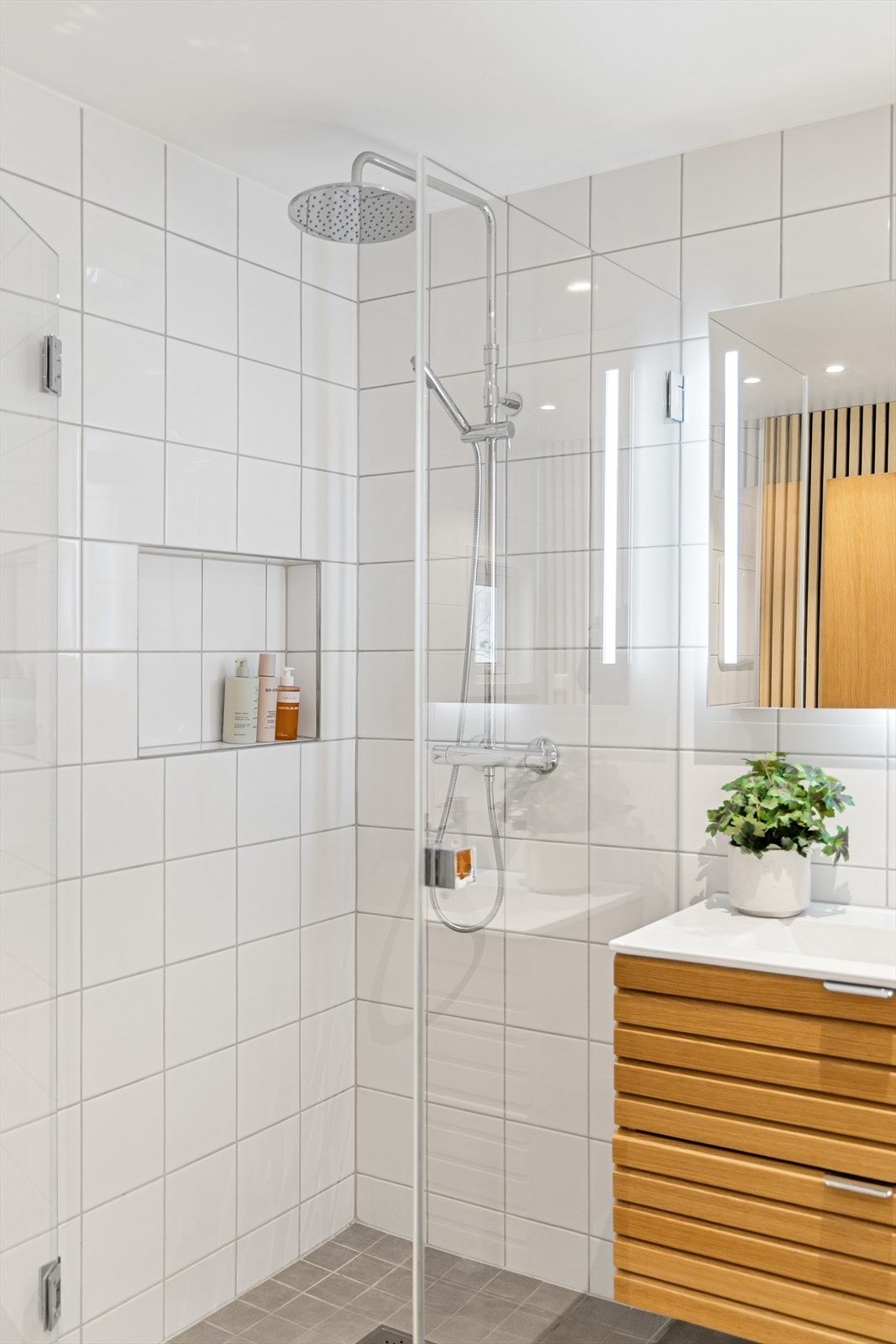 Romslig dusjhjørne med regnfallsdusj og innebygd hylle. Galleribilde