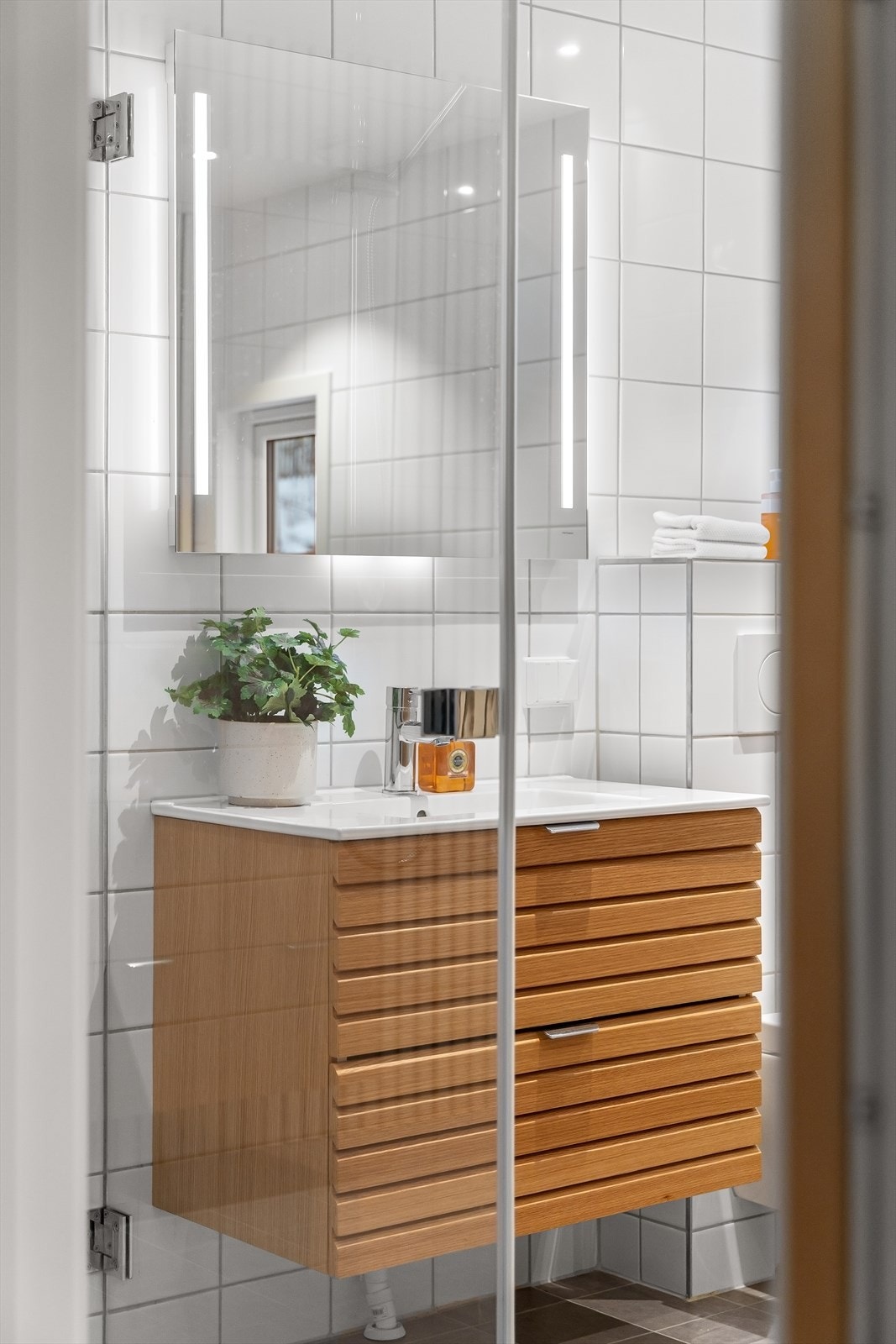 Badet har servant med innredning, vegghengt toalett, speil med lys og downlights i himling. Galleribilde