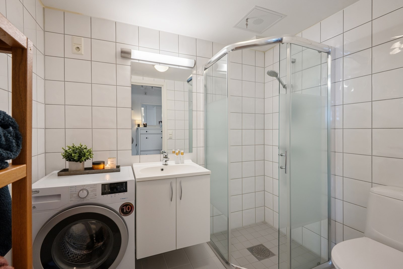 Baderom med lyse veggfliser og grå gulvfliser. Det er selvfølgelig gulvvarme for ekstra god komfort året rundt. Galleribilde