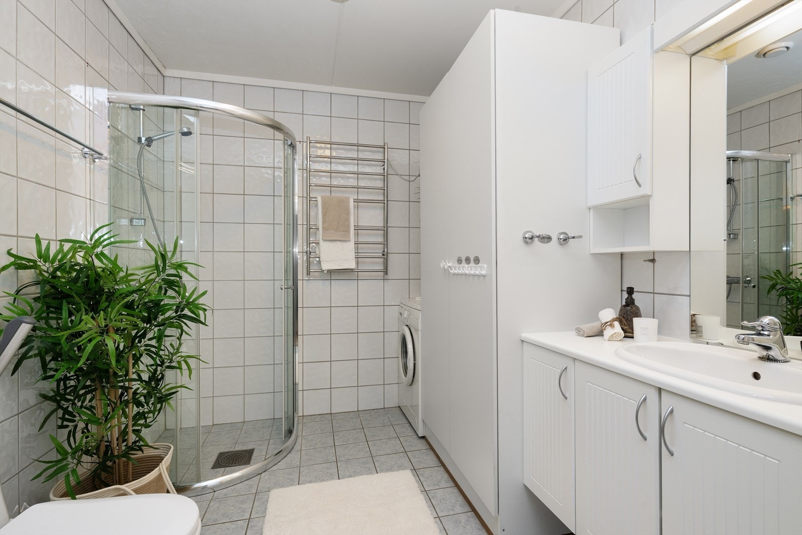 Lyst, flislagt bad med varmekabler, gulvmontert toalett og dusjhjørne med vegger i herdet glass. Romslig baderomsinnredning og opplegg for vaskemaskin. Galleribilde