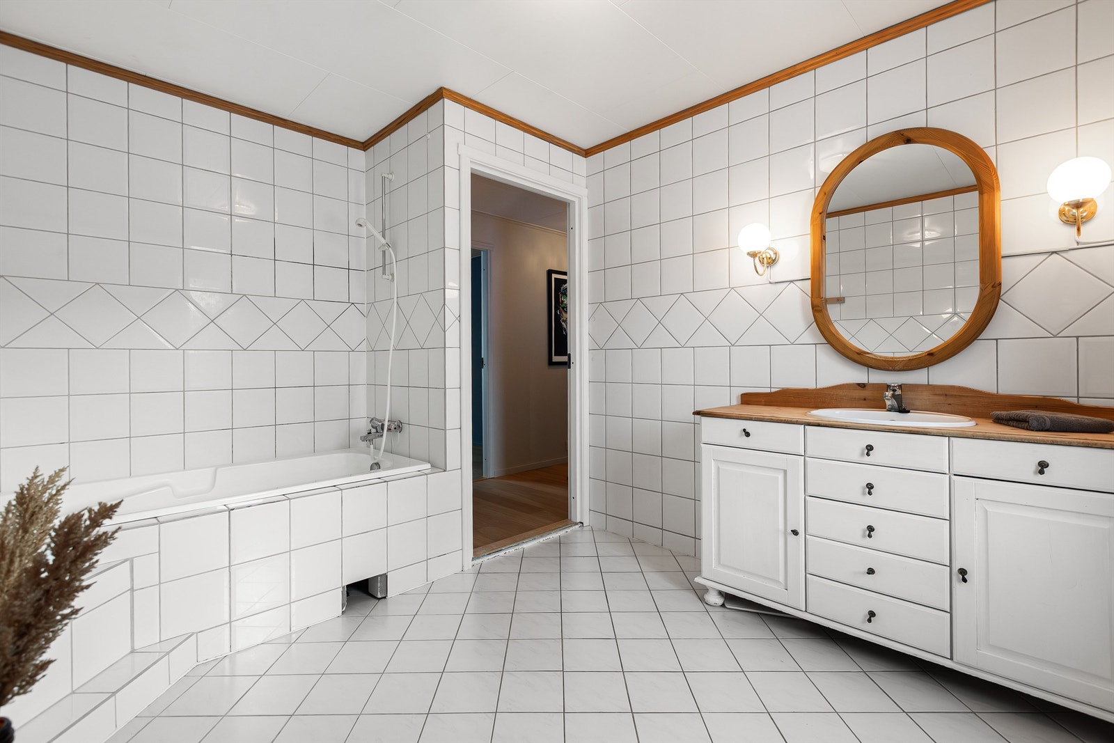 Badet har vegghengt servantskap med nedfelt servant og ett-greps armatur. Speil over servant med overlys. Innebygget badekar med dusjbatteri. Gulvmontert toalett. Galleribilde