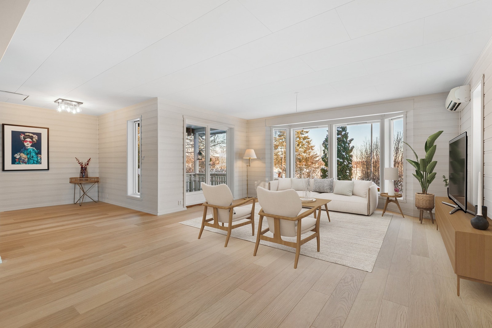 En åpen stue med vindusflater som slipper inn rikelig med dagslys. (Digitalt møblert) Galleribilde